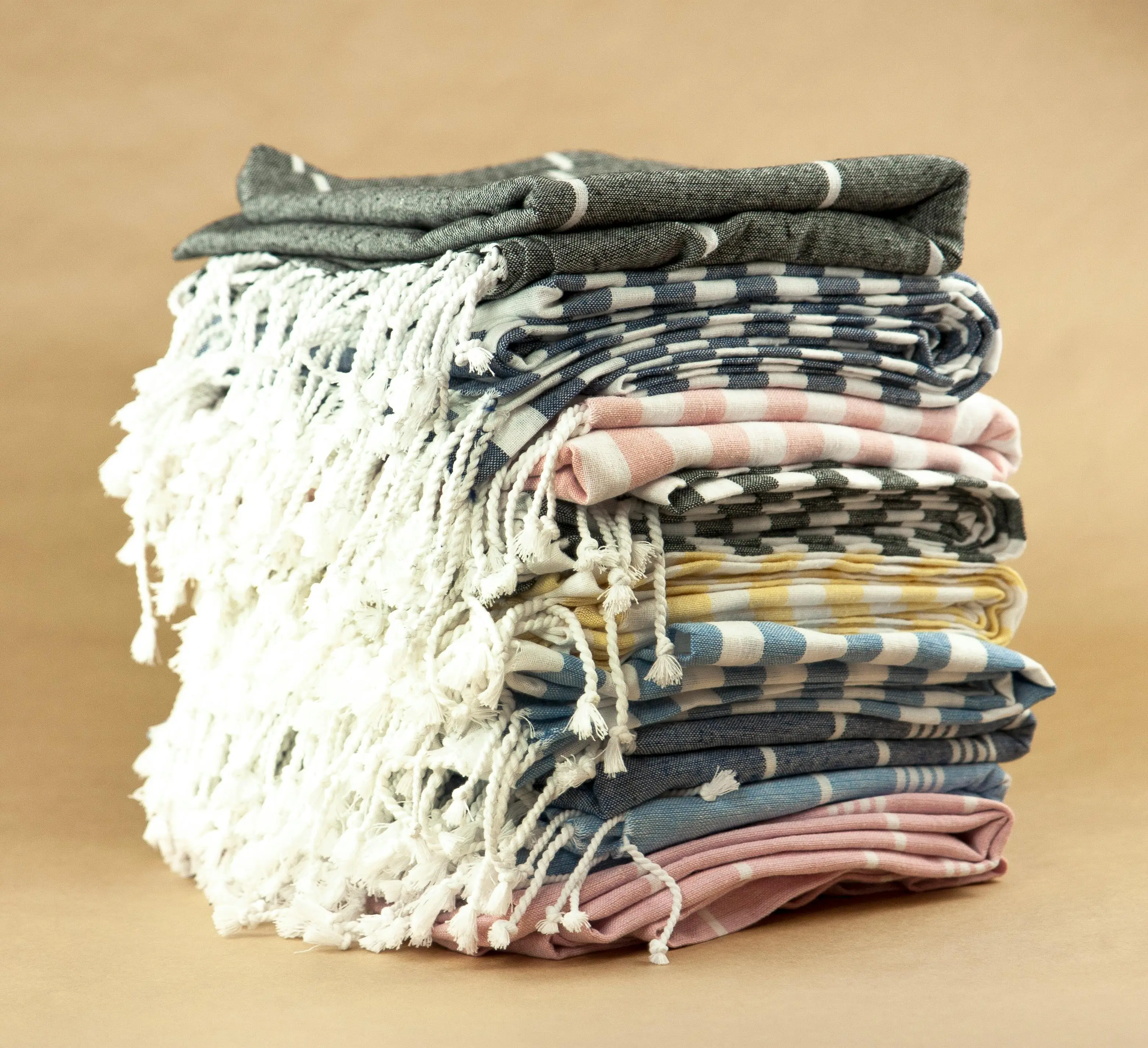 and paper towels A neatly stacked pile of colorful striped Turkish towels with fringe details.