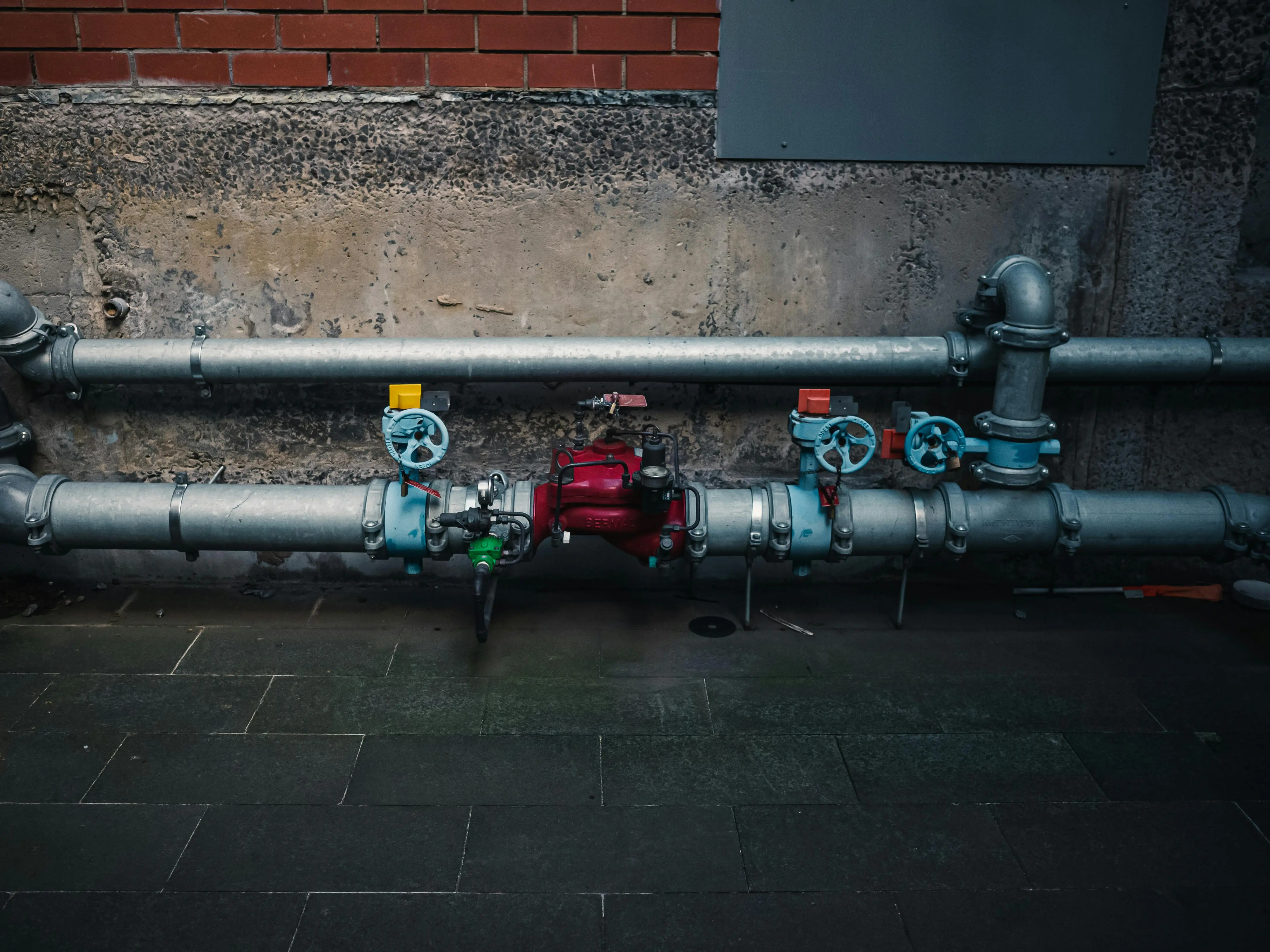 cost to replace shower valve A detailed view of industrial pipes with colorful valves on a textured wall.