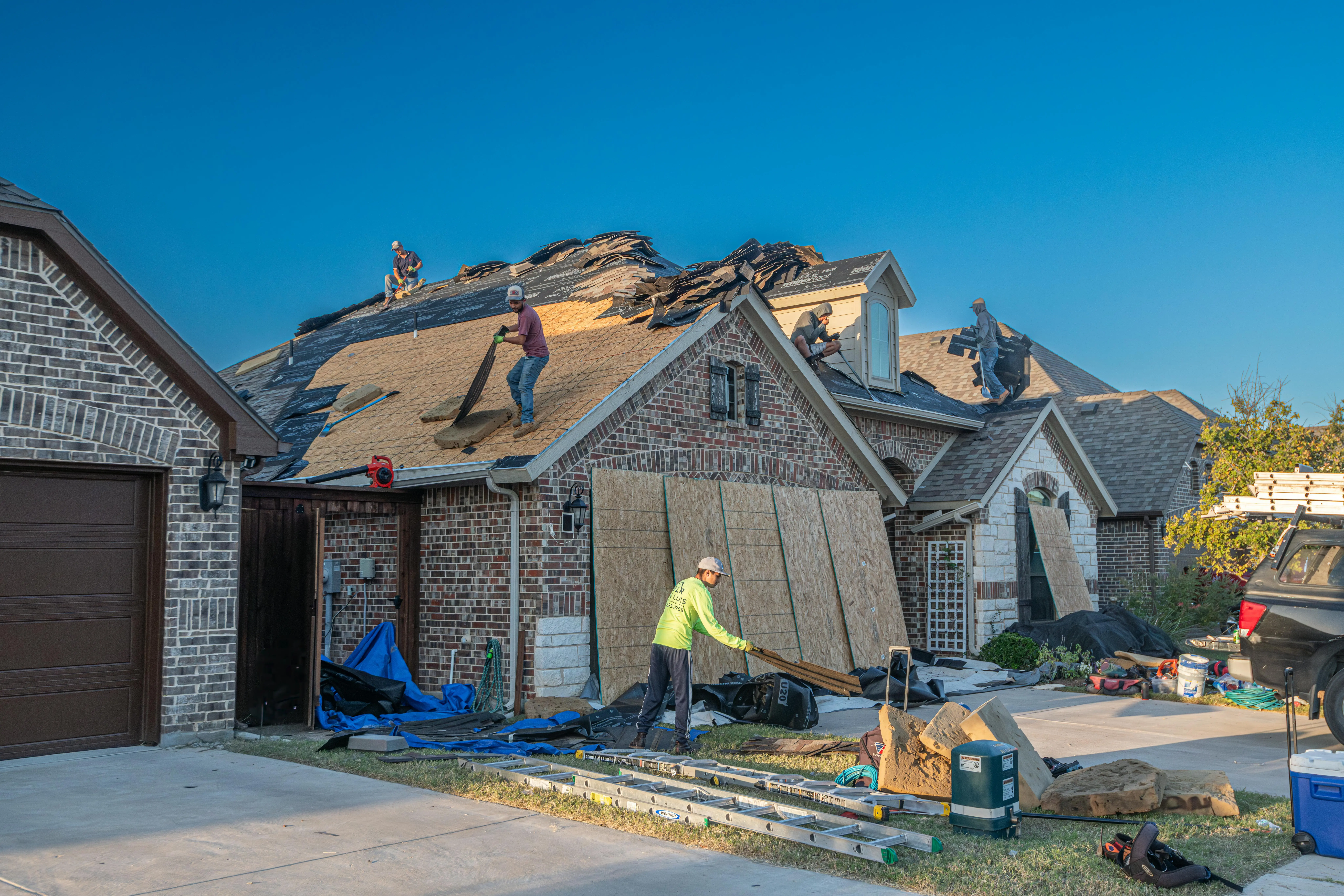 how much does it cost to side a house Workers engage in roof replacement on a brick house in Fort Worth, Texas.