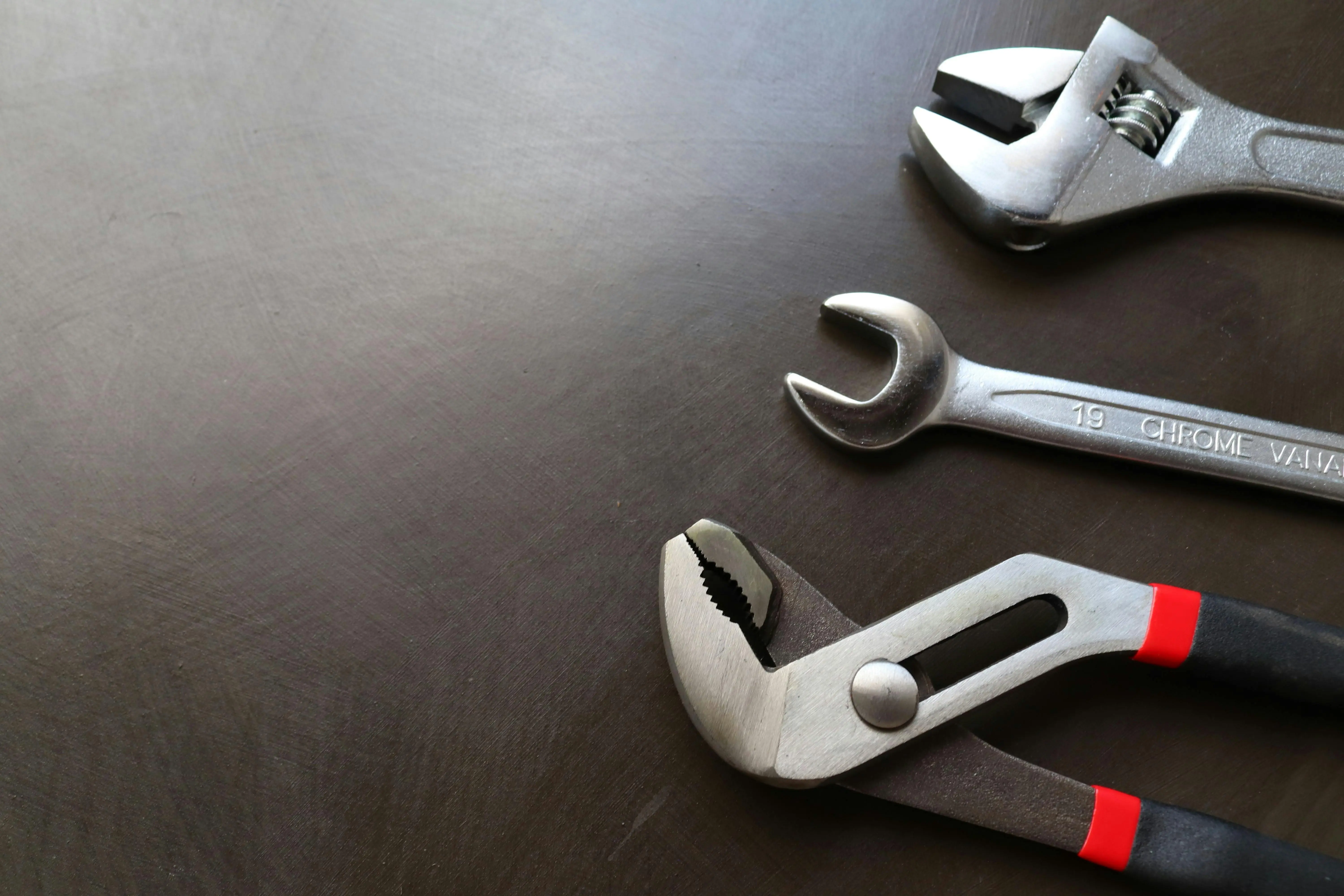 cracked sink repair High-quality image of various metal tools including wrenches and pliers arranged on a dark surface.