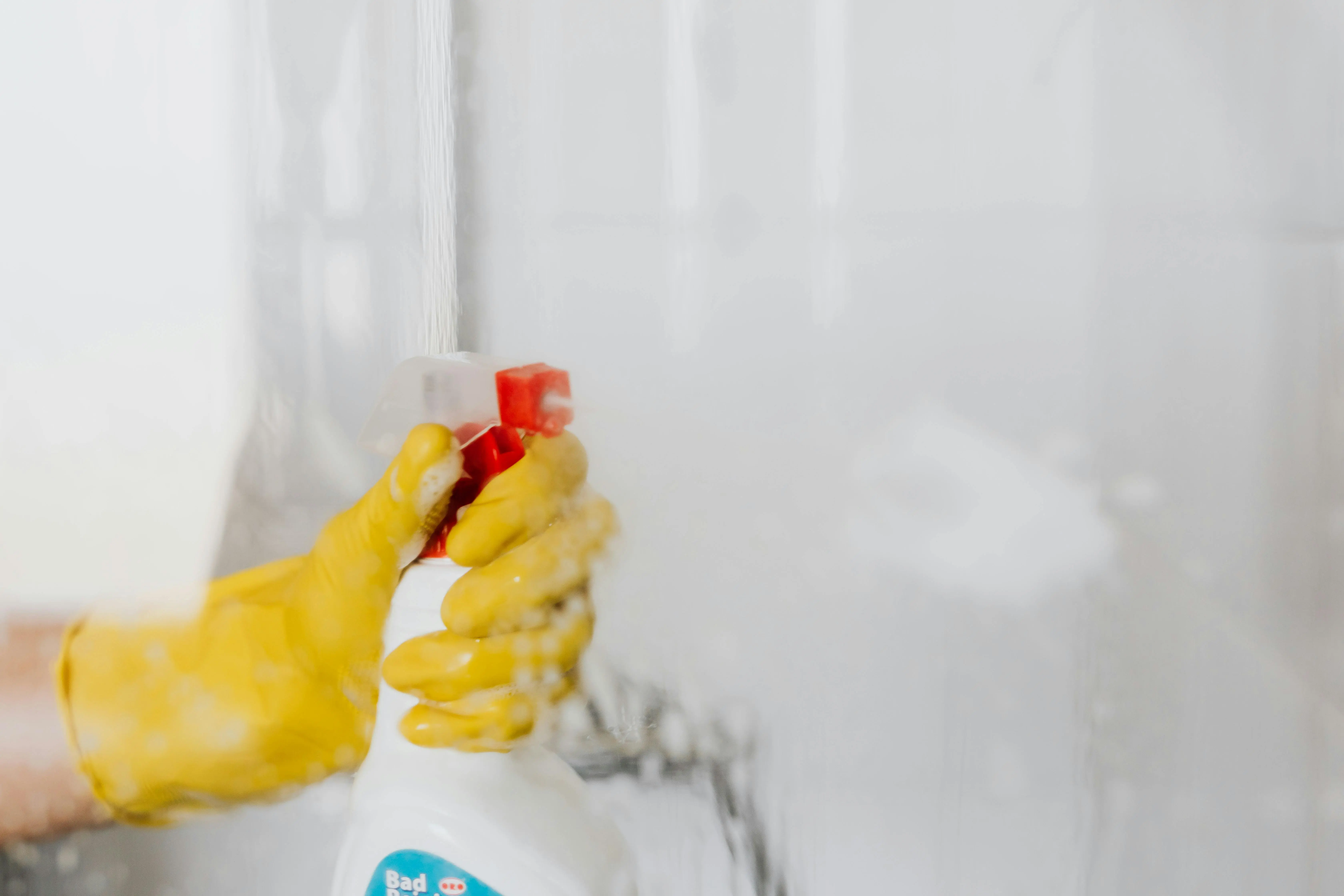 how to get tree sap out of clothes Crop unrecognizable person in yellow latex protective glove spraying detergent from bottle with plastic dispenser at glass of shower cabin