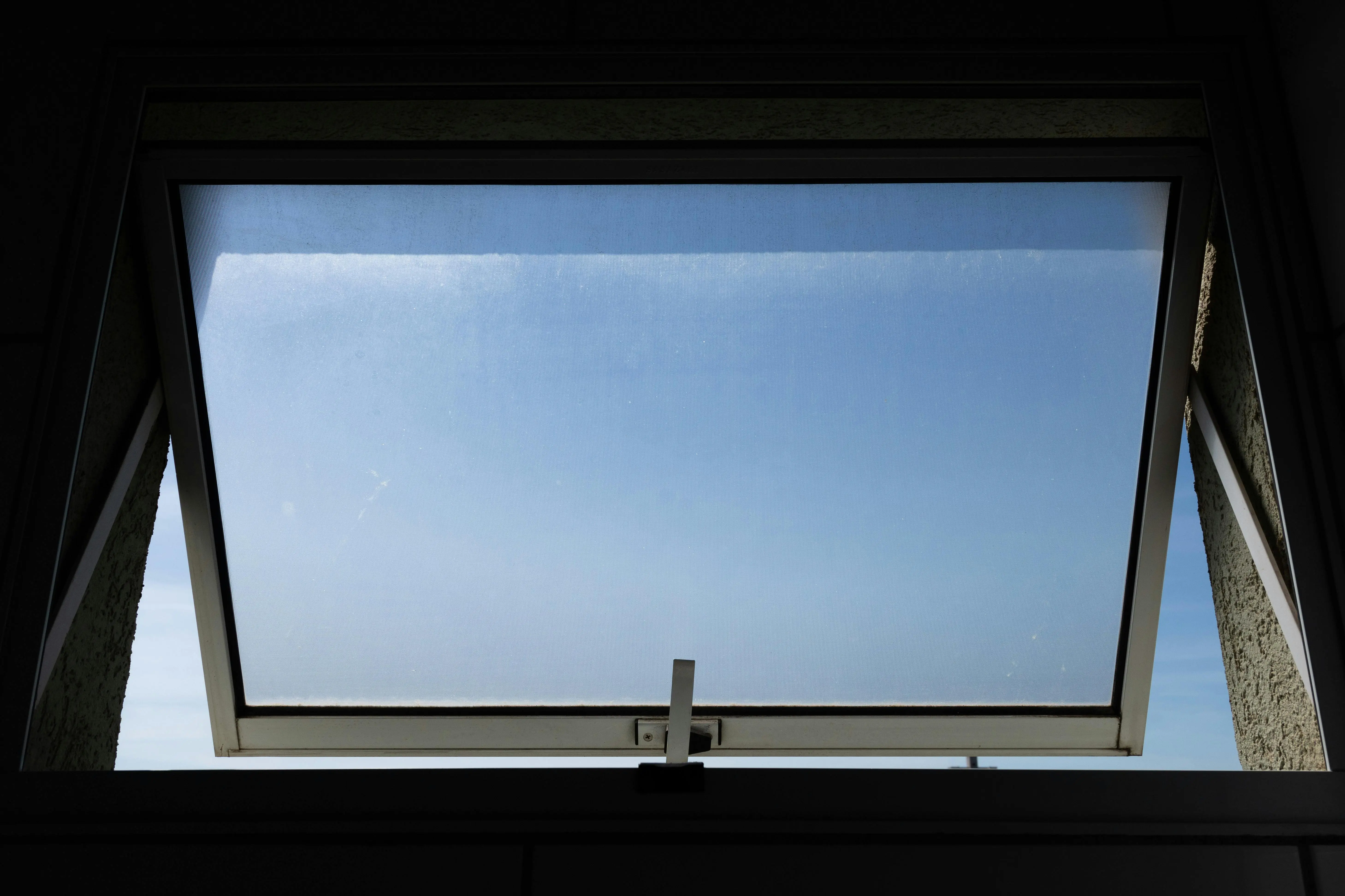 how to get rid of mildew smell in clothes A low angle view of an open skylight window revealing a clear blue sky.