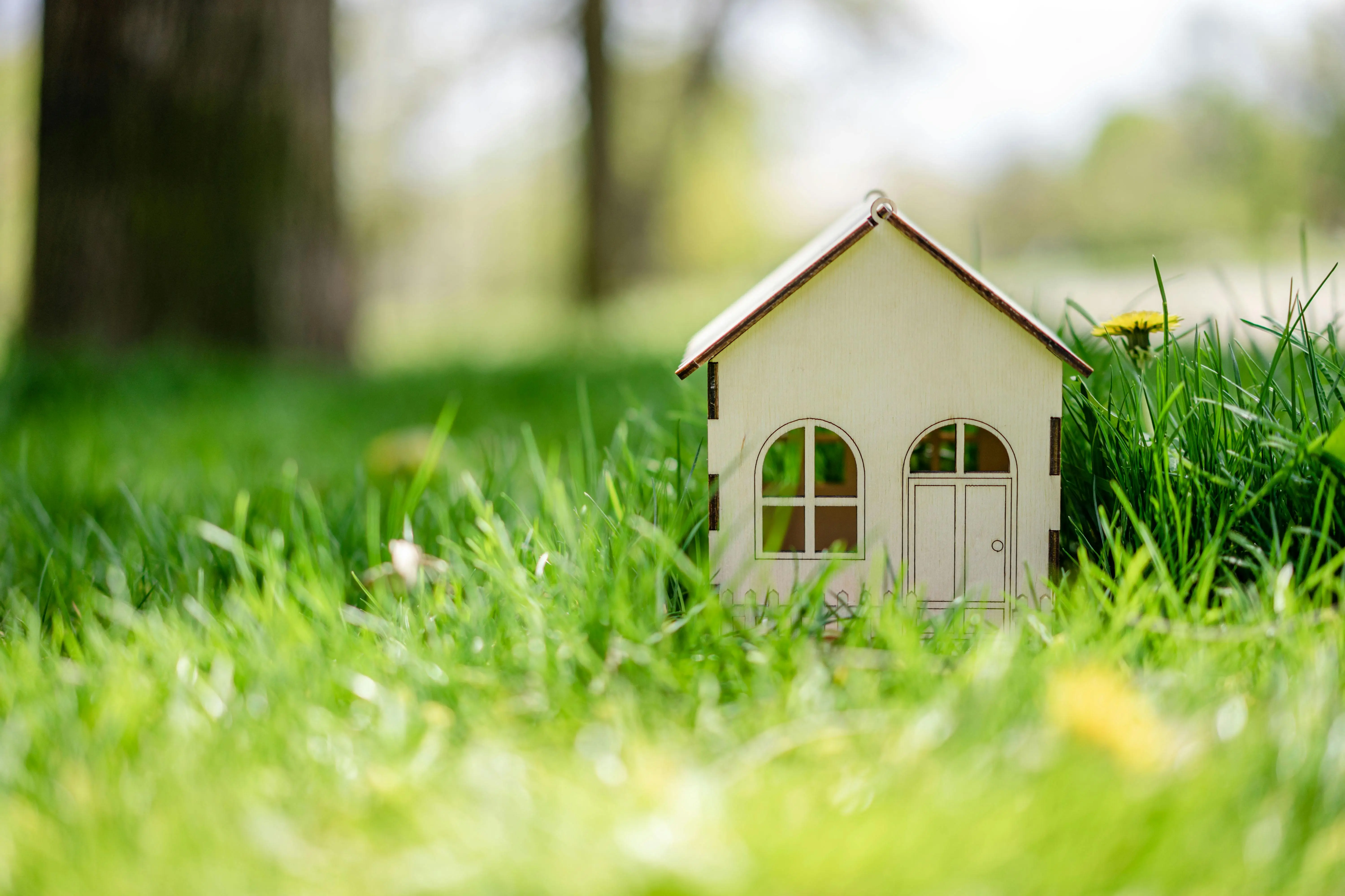 tiny house on foundation Close-up of a small toy house nestled in vibrant green grass, depicting a playful outdoor scene.