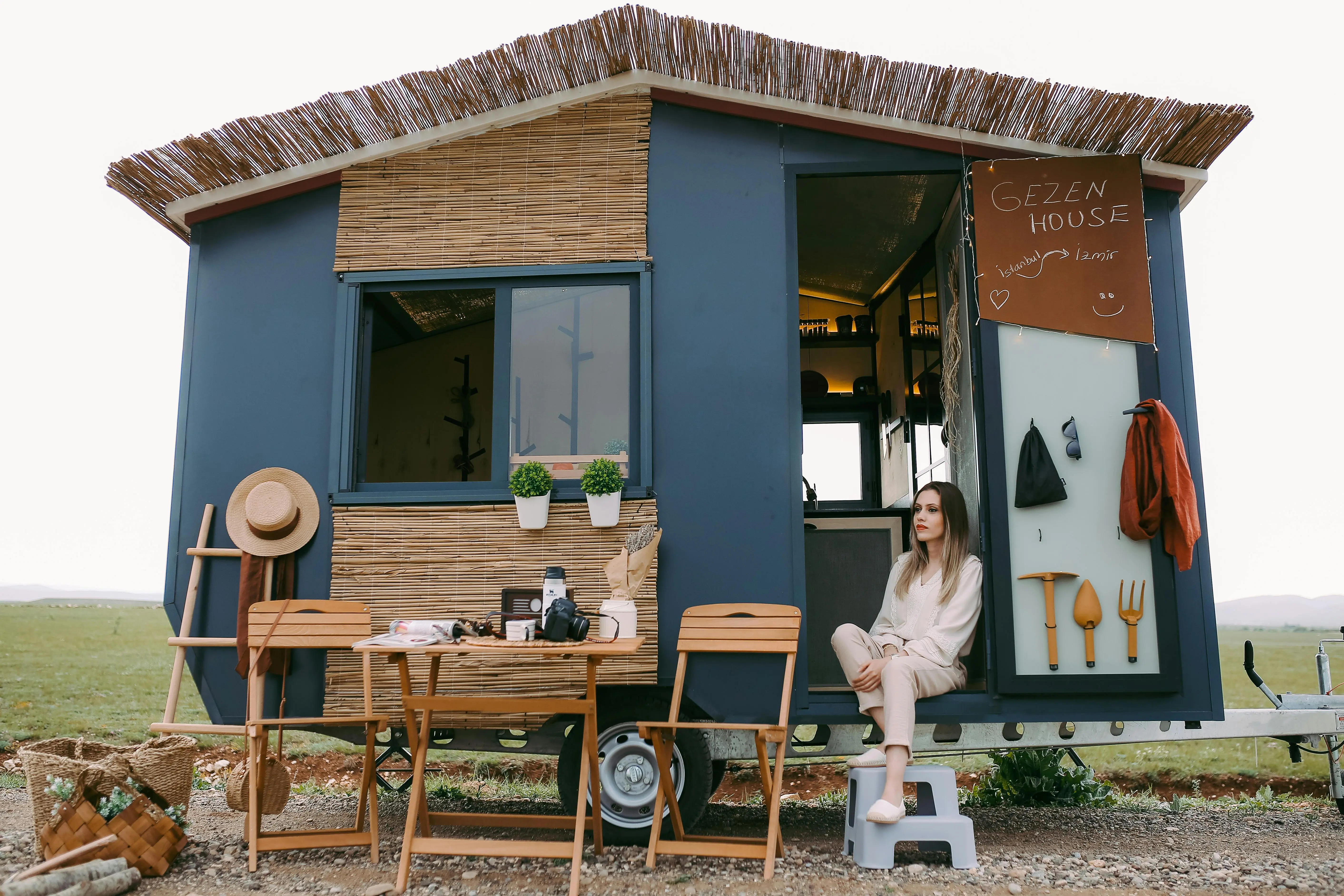 tiny house on foundation A woman enjoys a peaceful moment in a stylish mobile home, showcasing boho design.