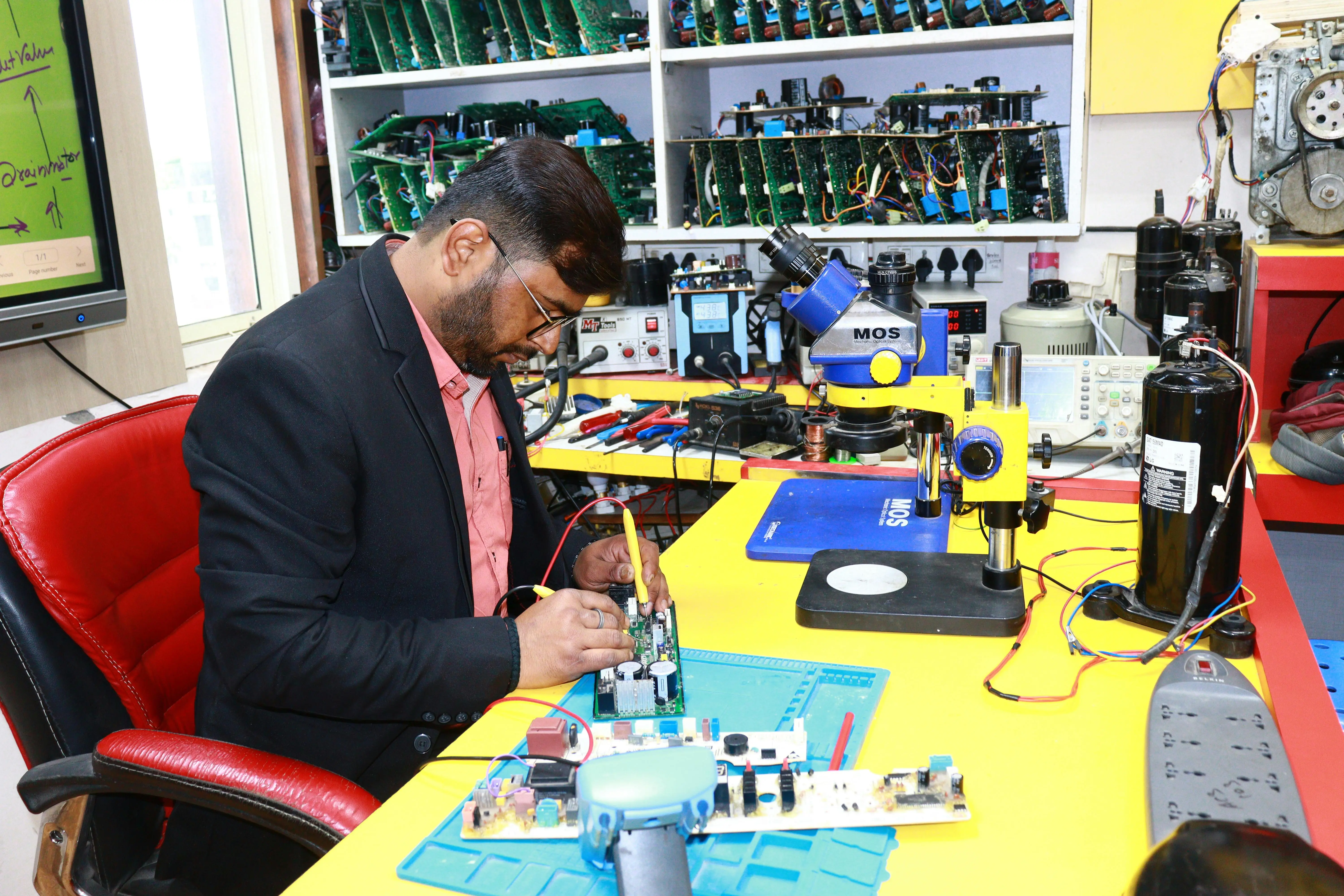 how to clean evaporator coil A focused technician repairs a circuit board in a high-tech electronics workshop.