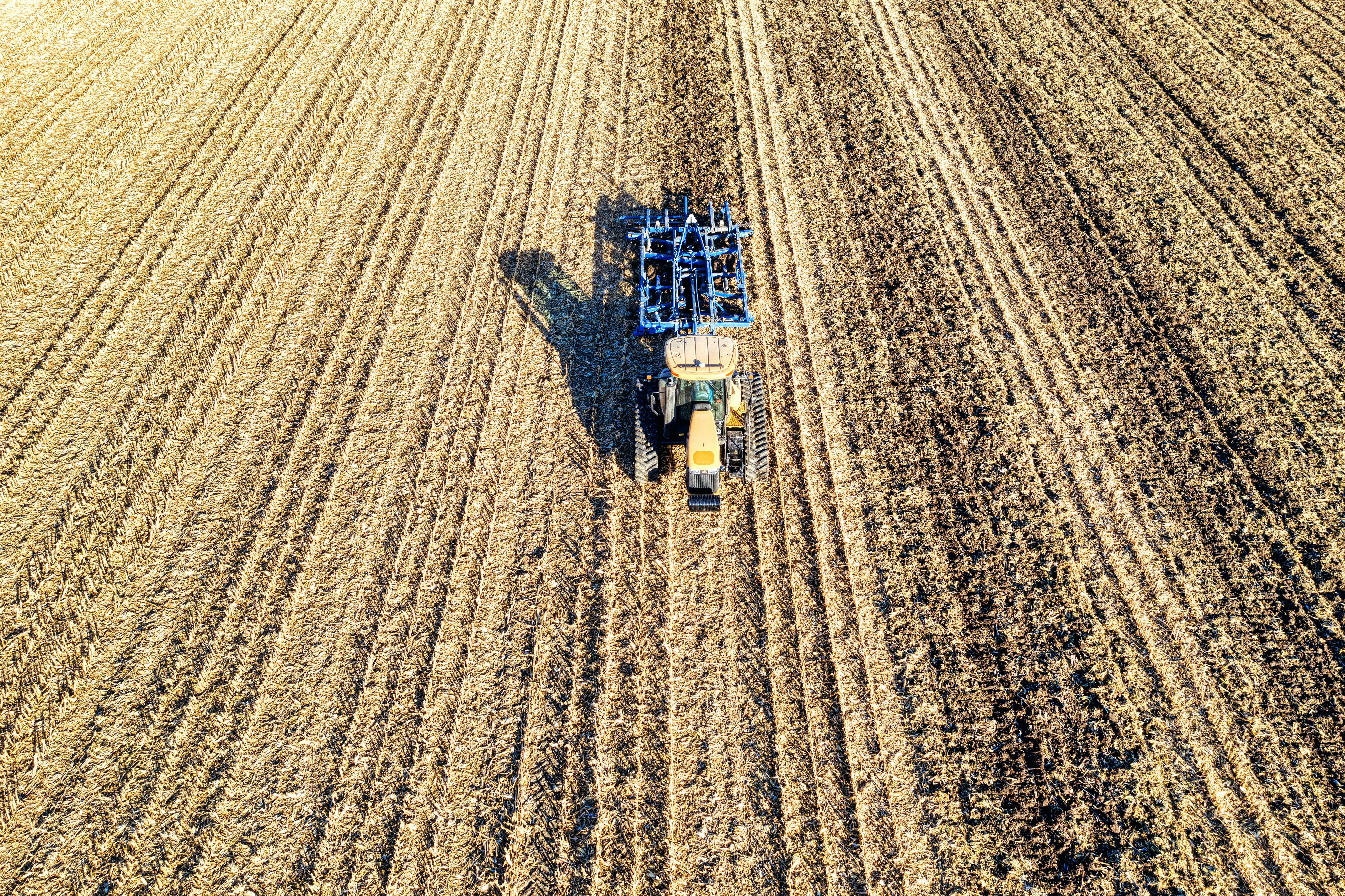soil probe Aerial view of a tractor plowing a vast farmland in Minnesota, USA, during daytime.