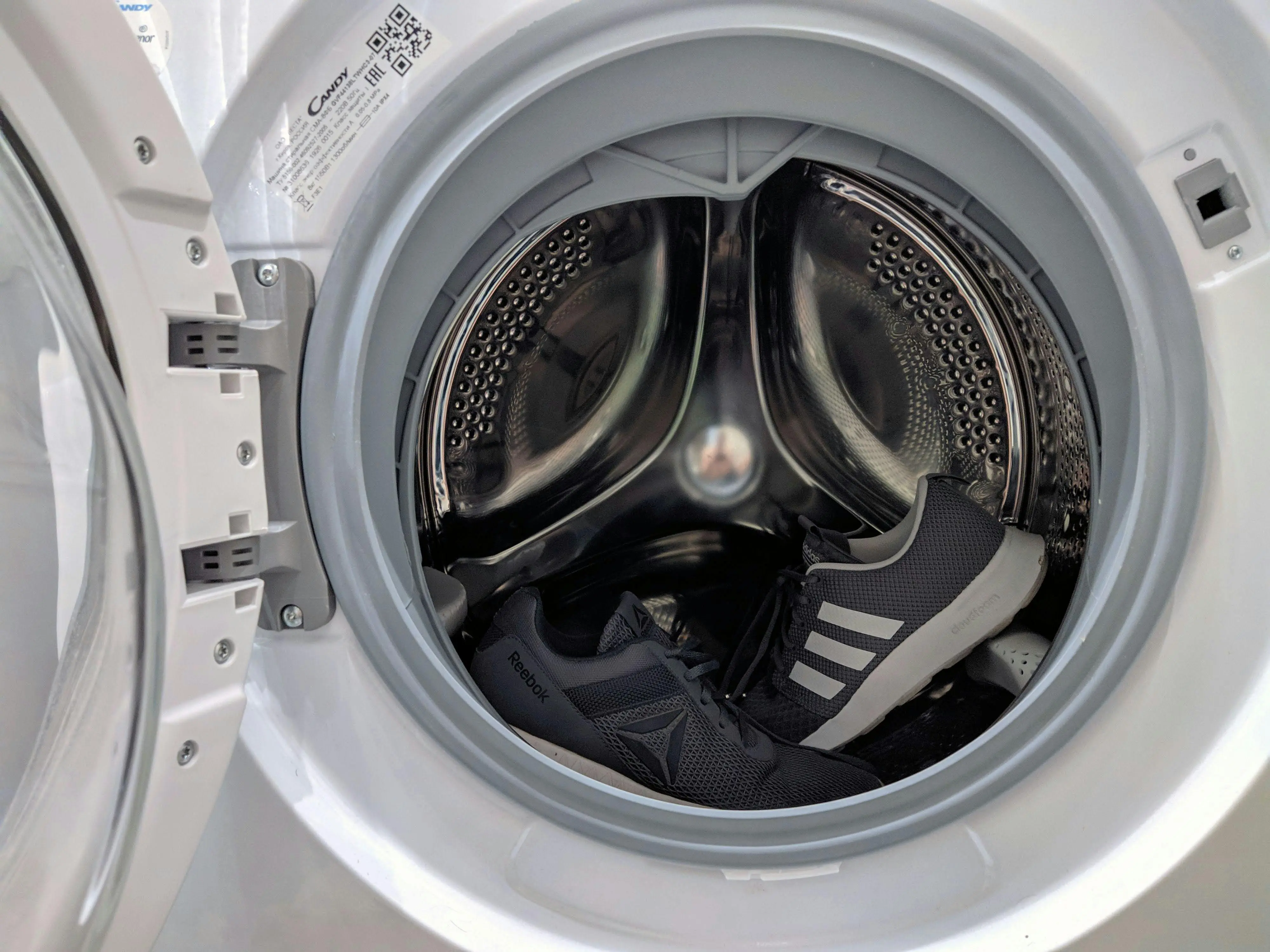 how to get urine smell out of clothes Close-up of black sneakers inside a washing machine drum showcasing laundry theme.