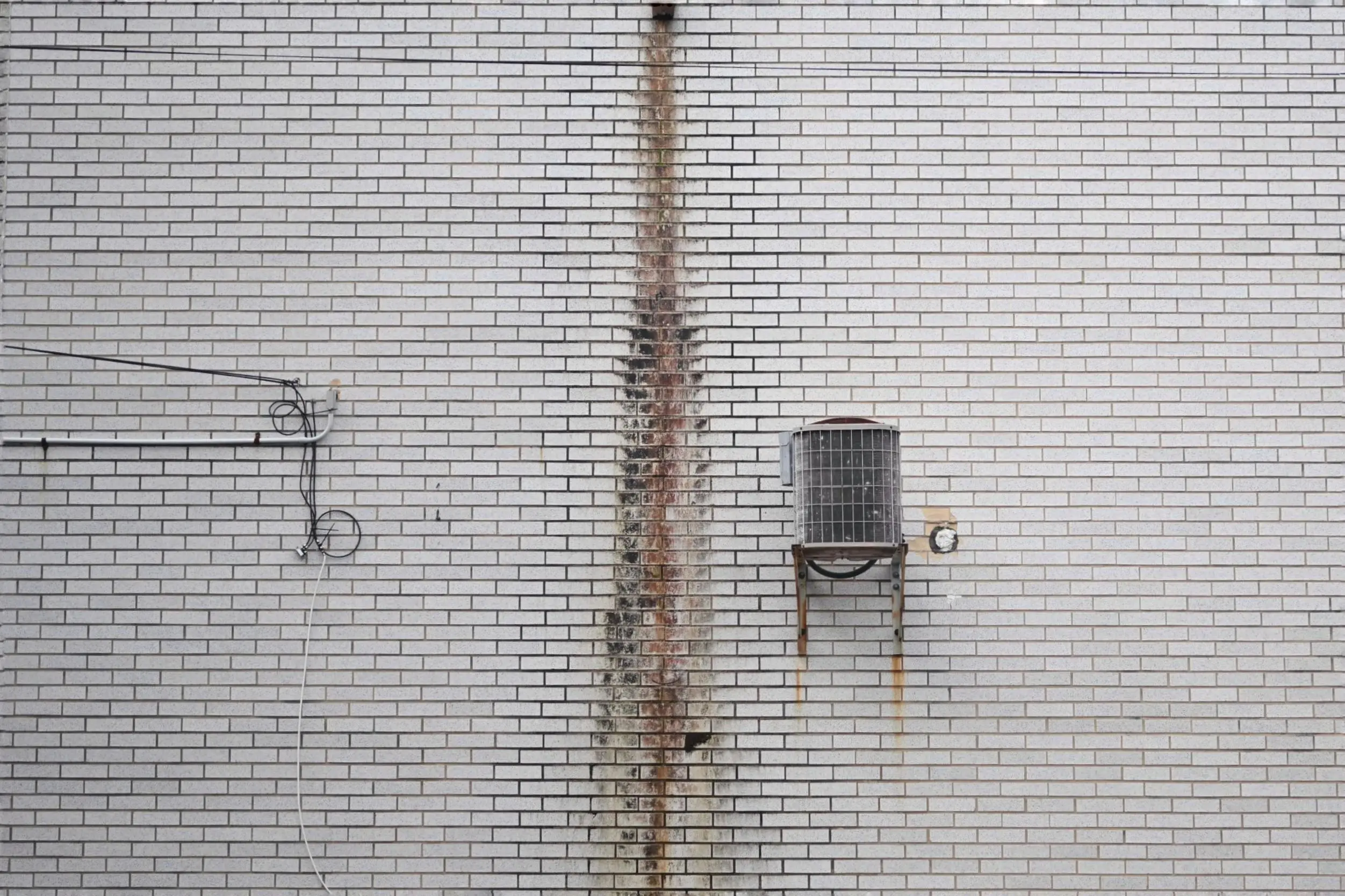 ac stopped working Close-up of a rusted air conditioning unit on a white brick wall for industrial themes.