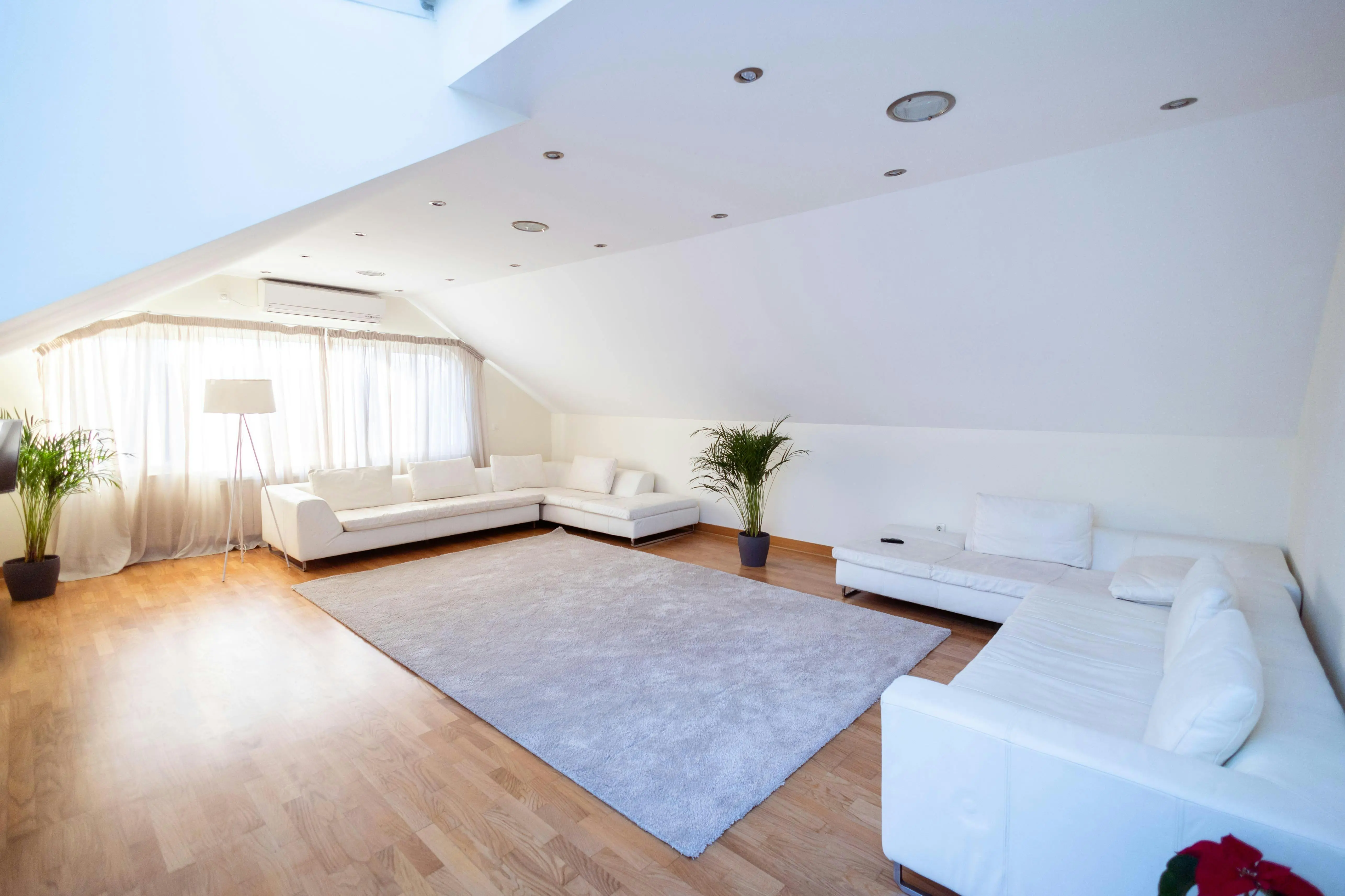 tiny home tips and tricks Bright and airy modern living room with white sofas, plants, and wooden flooring.