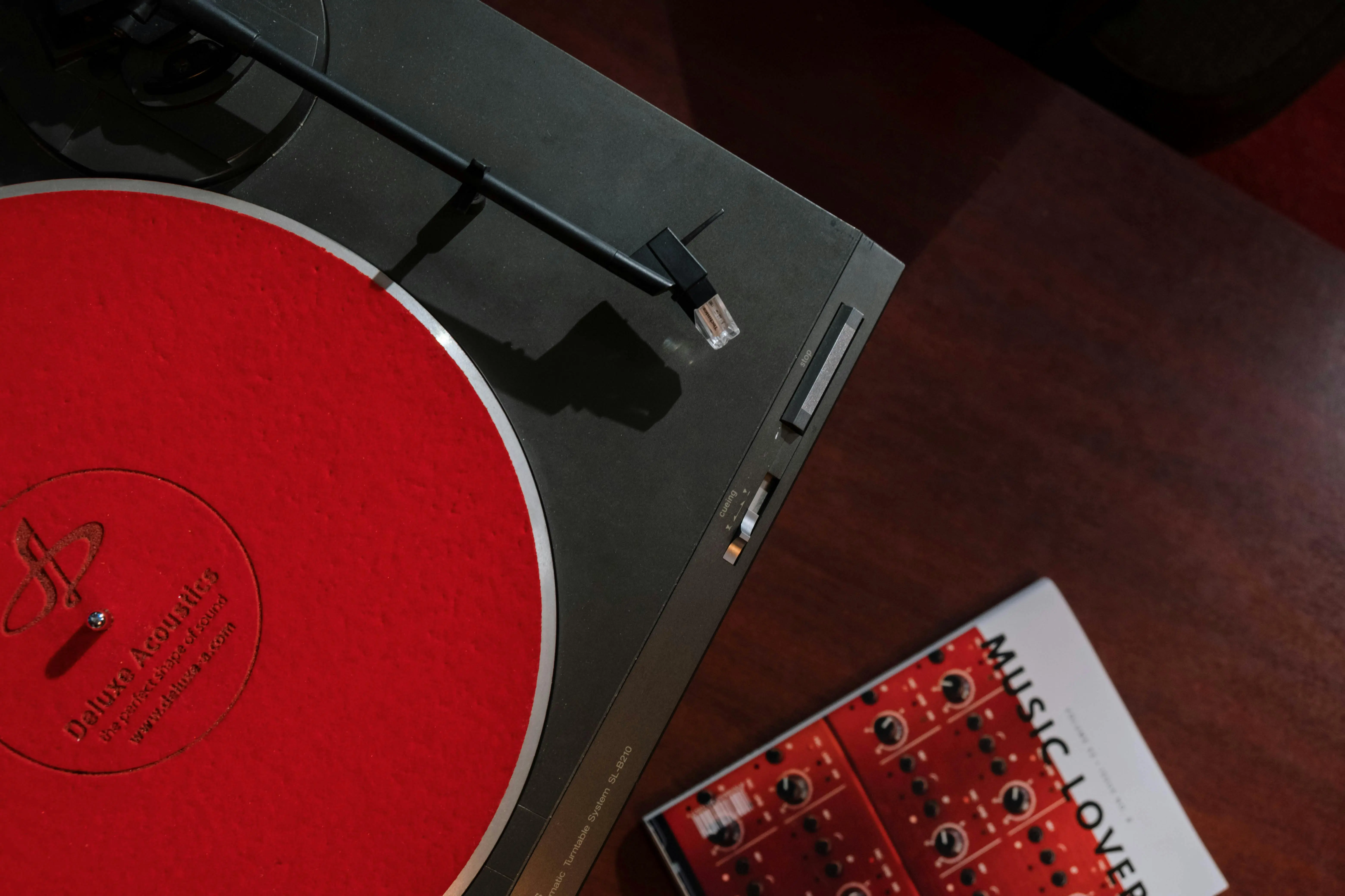 turntable and vinyl stand Top view of a turntable with red slipmat and music magazine, perfect for audiophile enthusiasts.