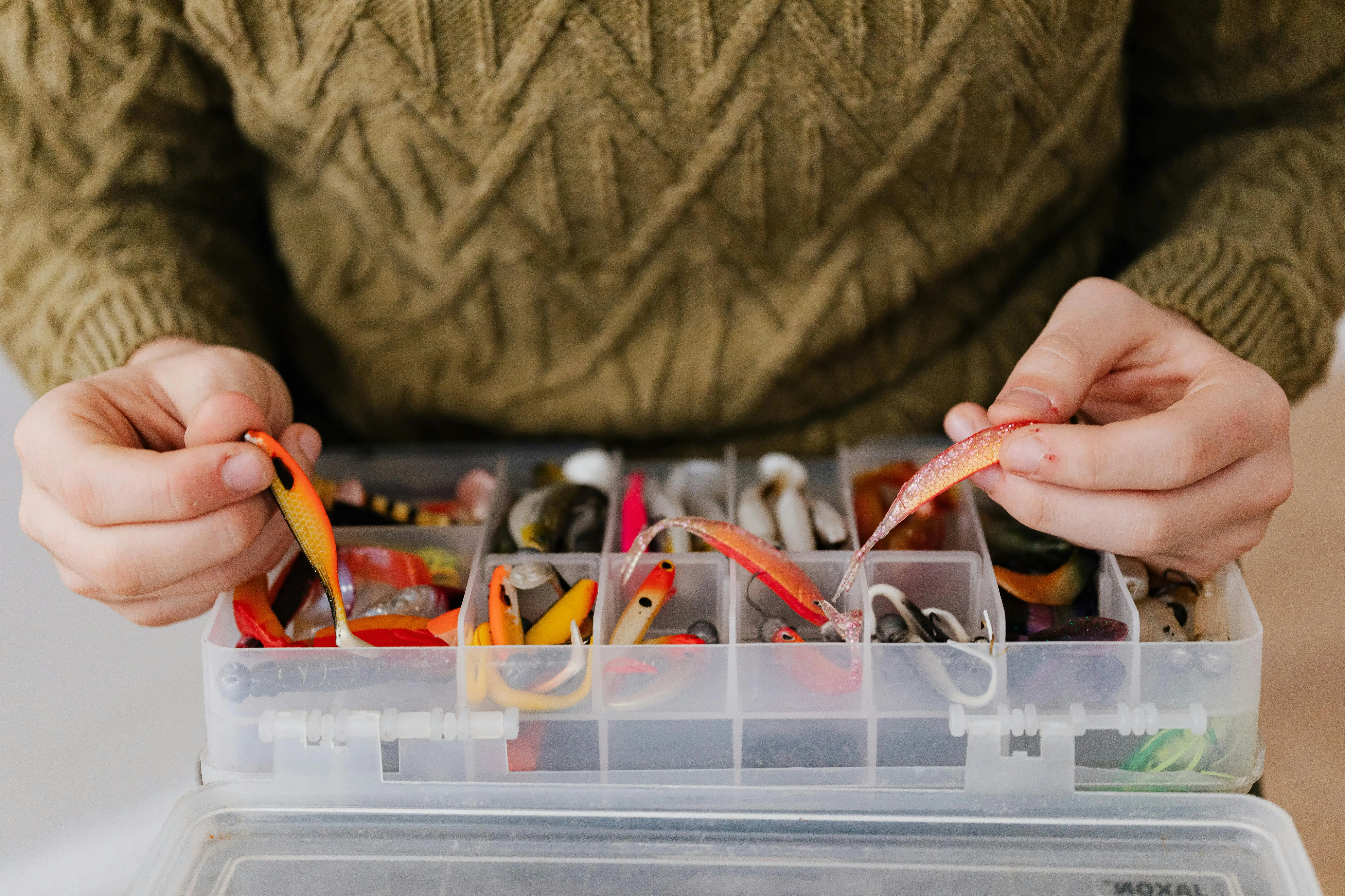 mouse bait stations Close-up of hands organizing colorful fishing lures in a tackle box, perfect for anglers.