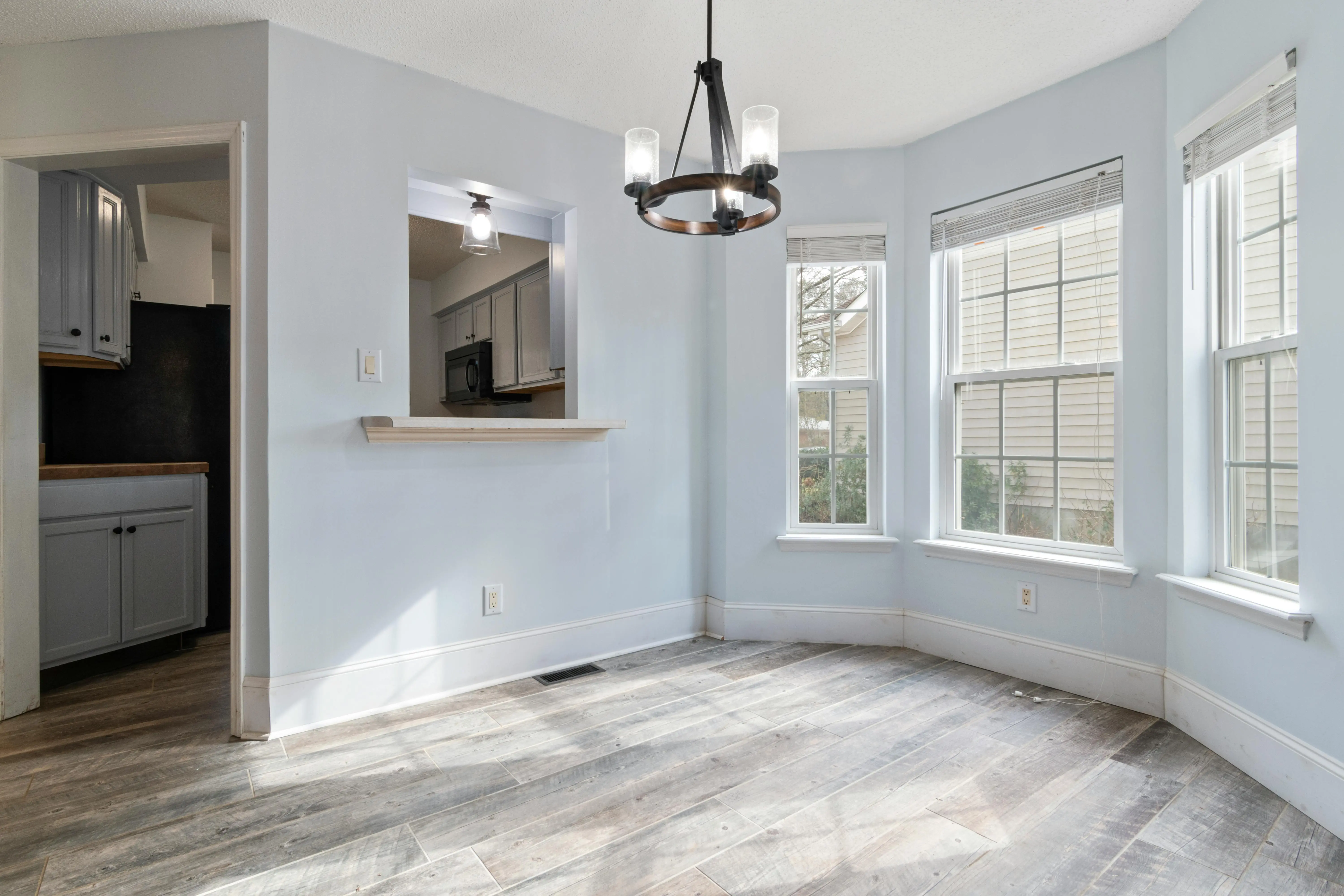 garage doors with windows Sunlit empty room featuring a modern chandelier and wooden floors, ideal for home staging.