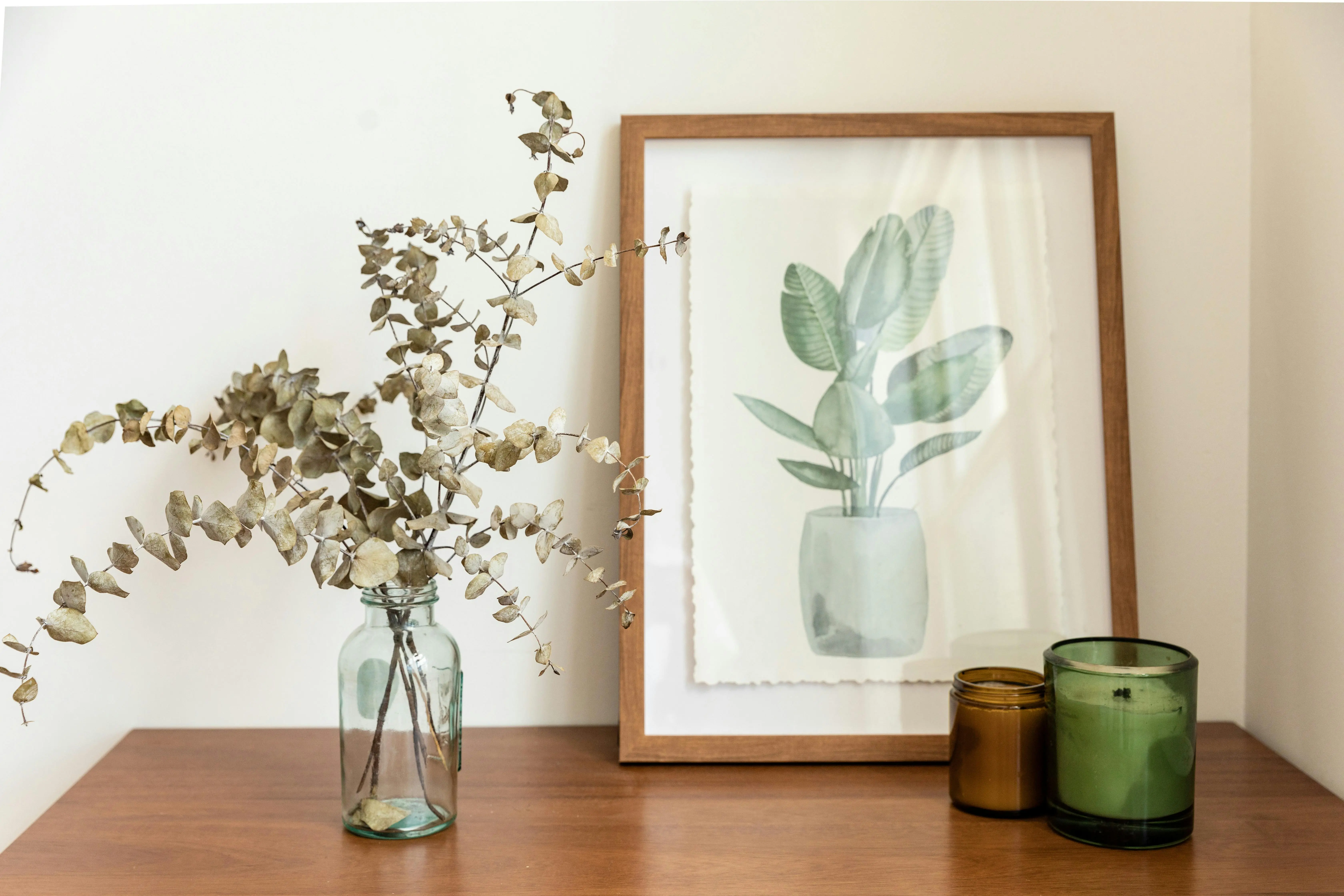 wall sculpture Minimalist interior with a eucalyptus arrangement, framed botanical print, and candles.