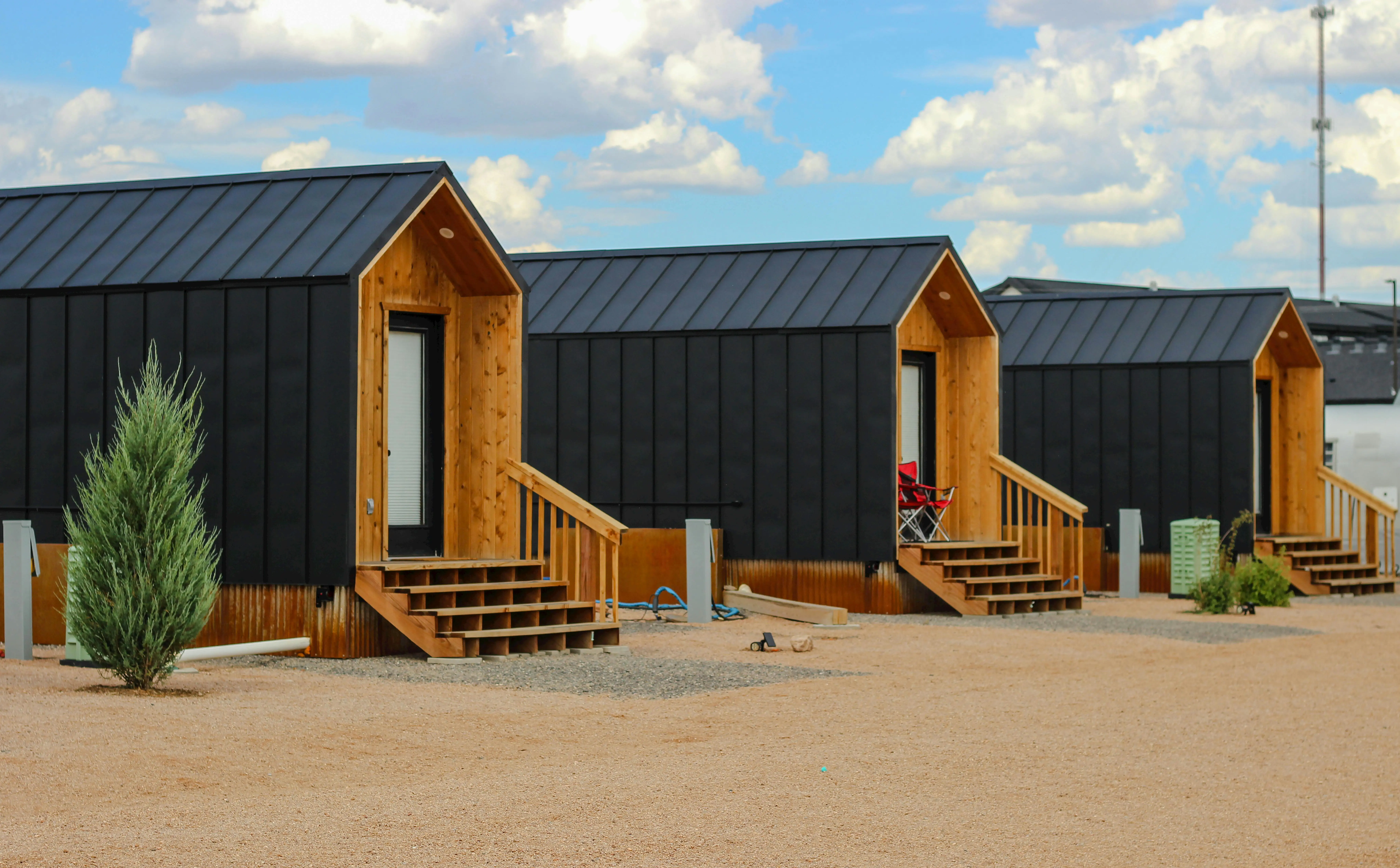 tiny home tips Row of modern black tiny houses in a desert setting under a cloudy sky.