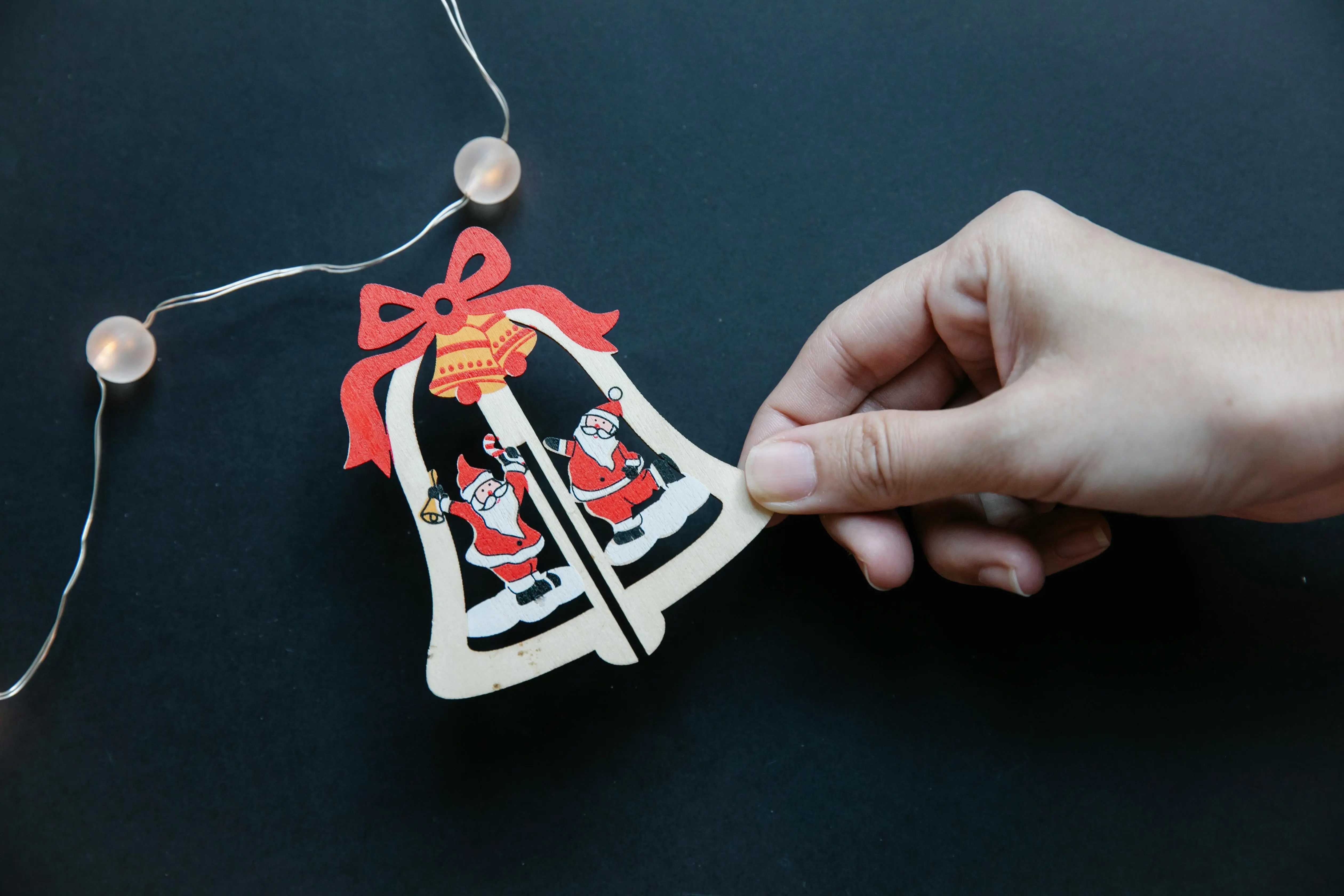 christmas holiday themes From above of unrecognizable woman holding little cute carton Christmas bell while making handmade garland