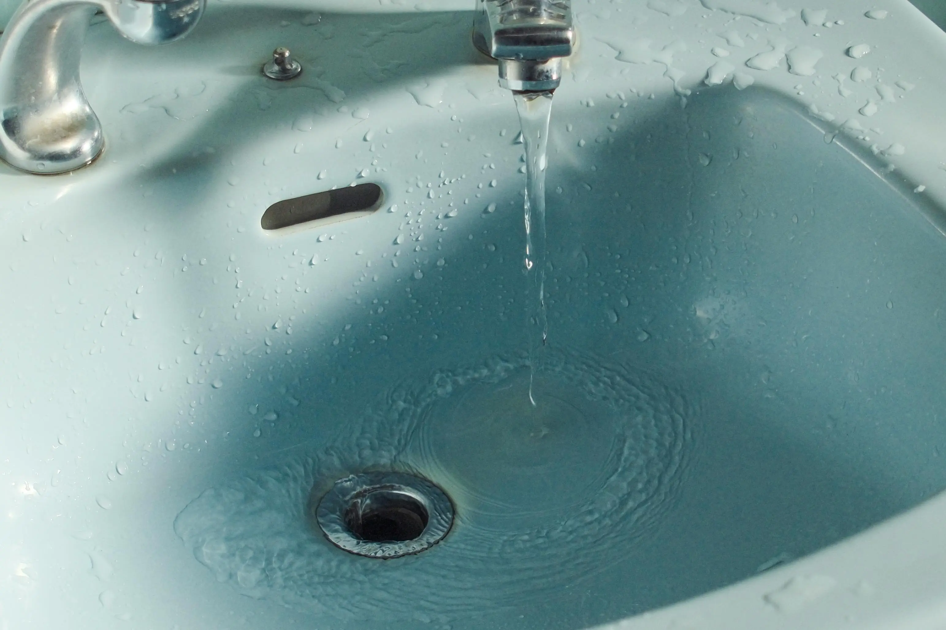 sink parts Close-up of water flowing from a faucet into a bathroom sink.