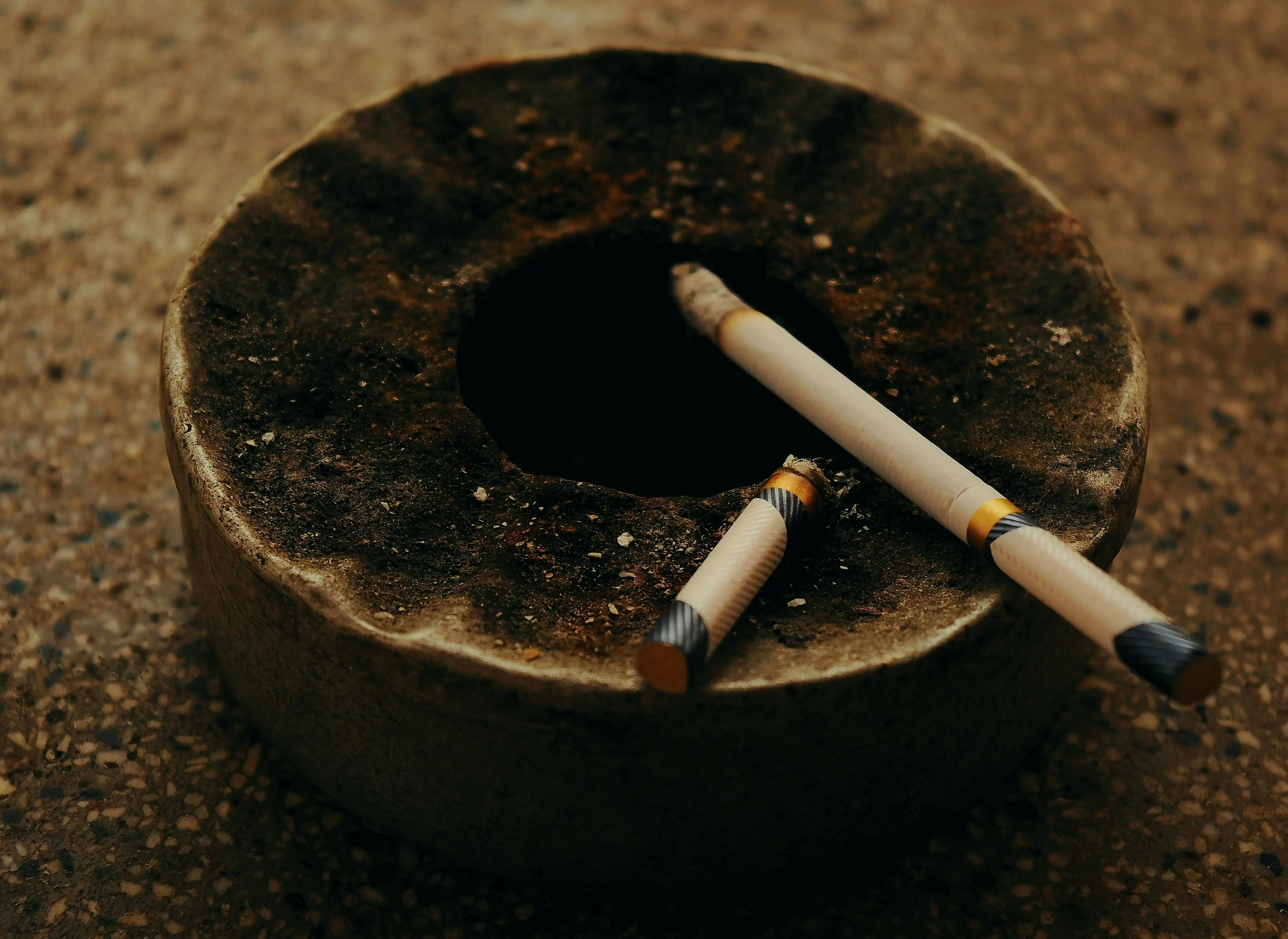 ac stopped working An antique ashtray with two burnt cigarettes on a textured surface, creating a moody atmosphere.