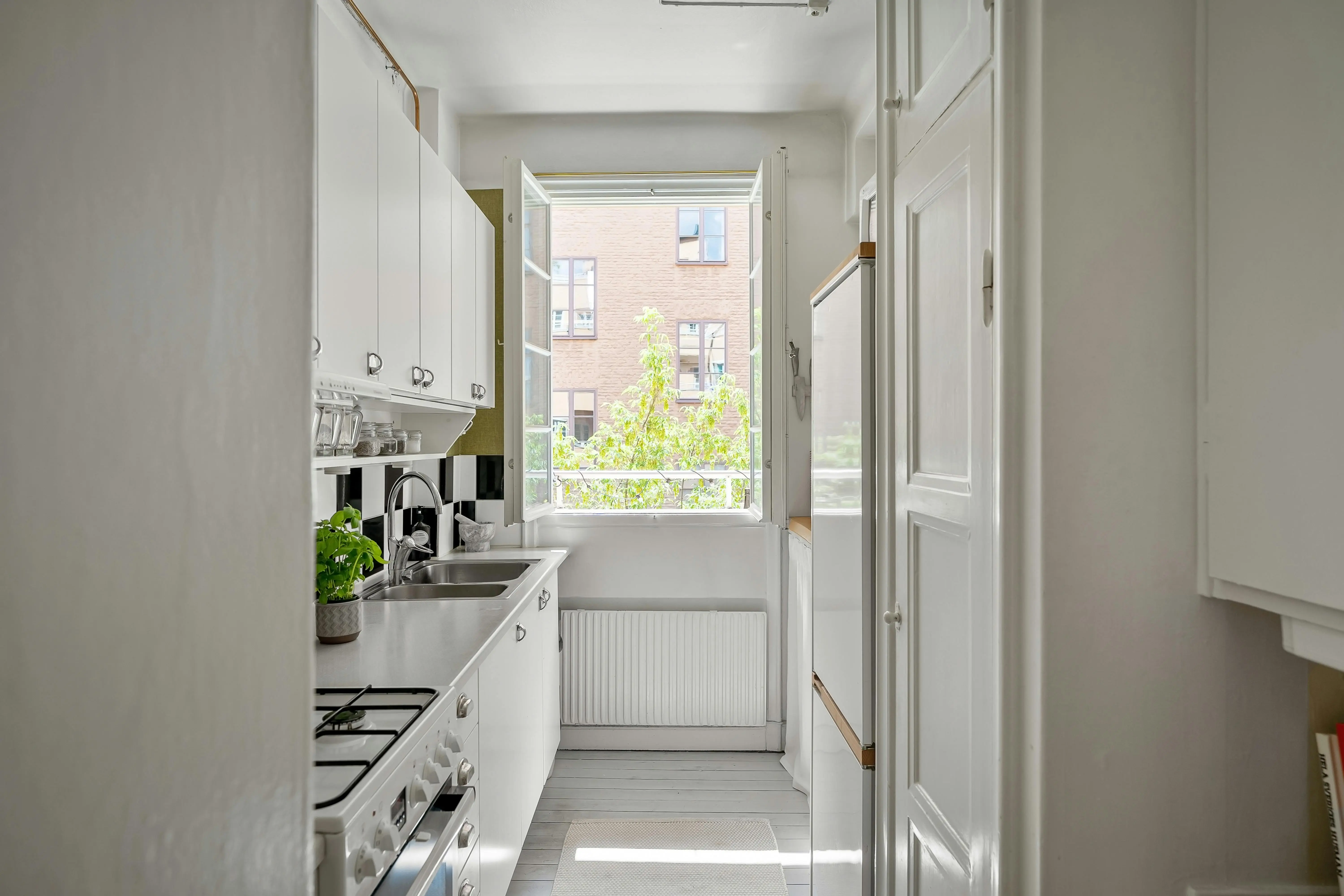 tiny home kitchen A bright and contemporary small kitchen with white cabinets and open window.