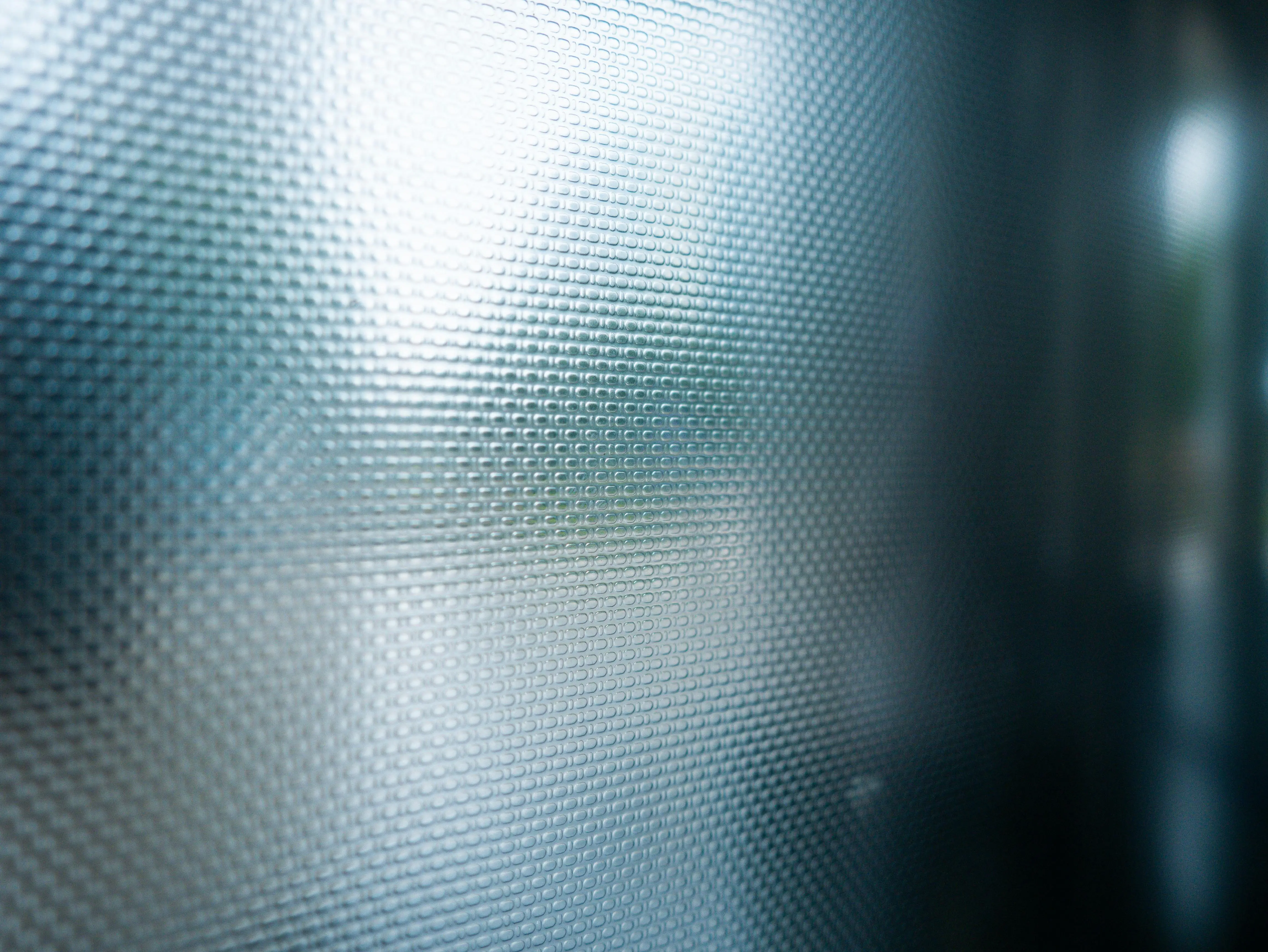 glass on tile Detailed close-up of a textured smoked glass panel with a soft light reflection.