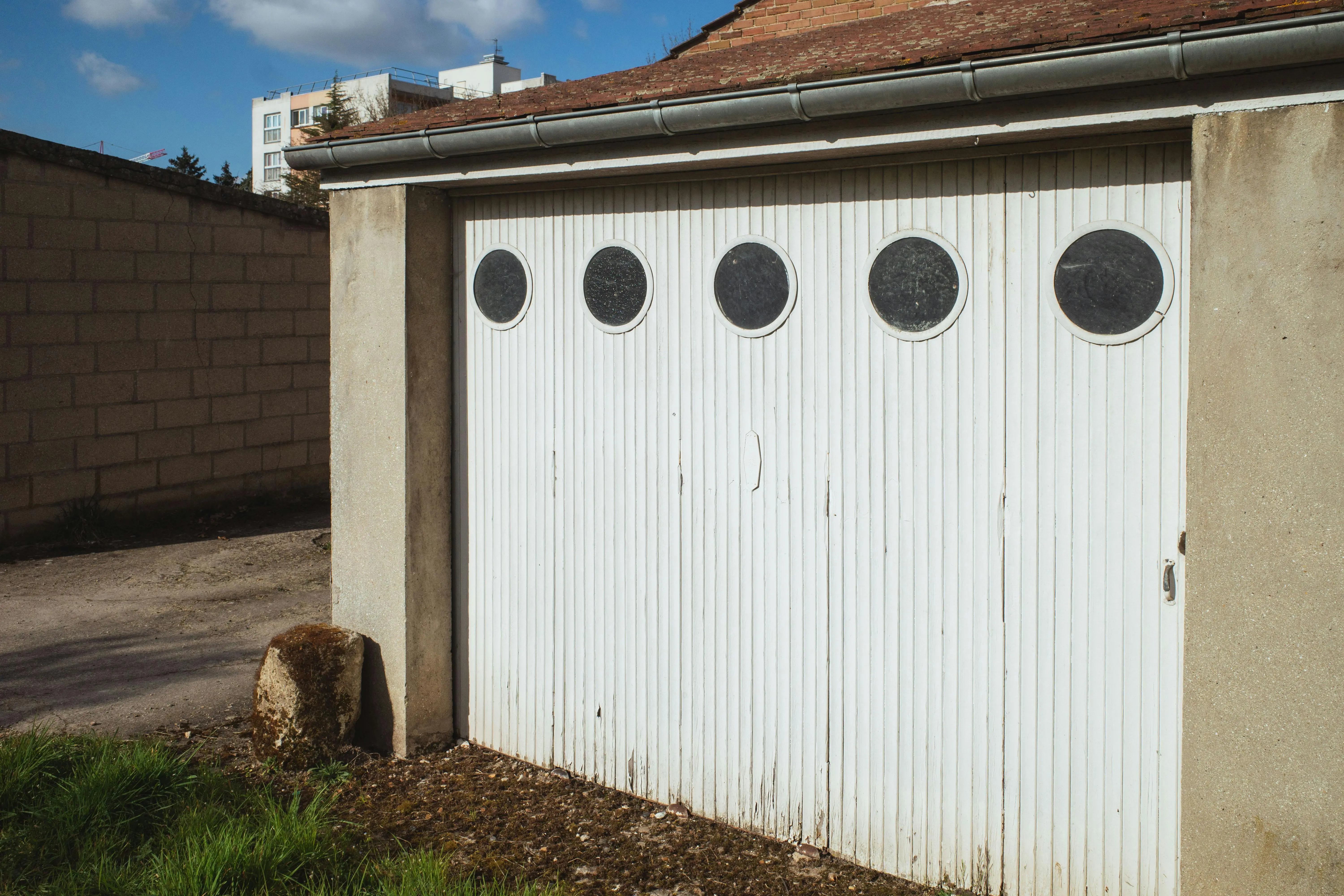 garage doors with windows White garage door with circular windows in a residential area of Compiègne, France.