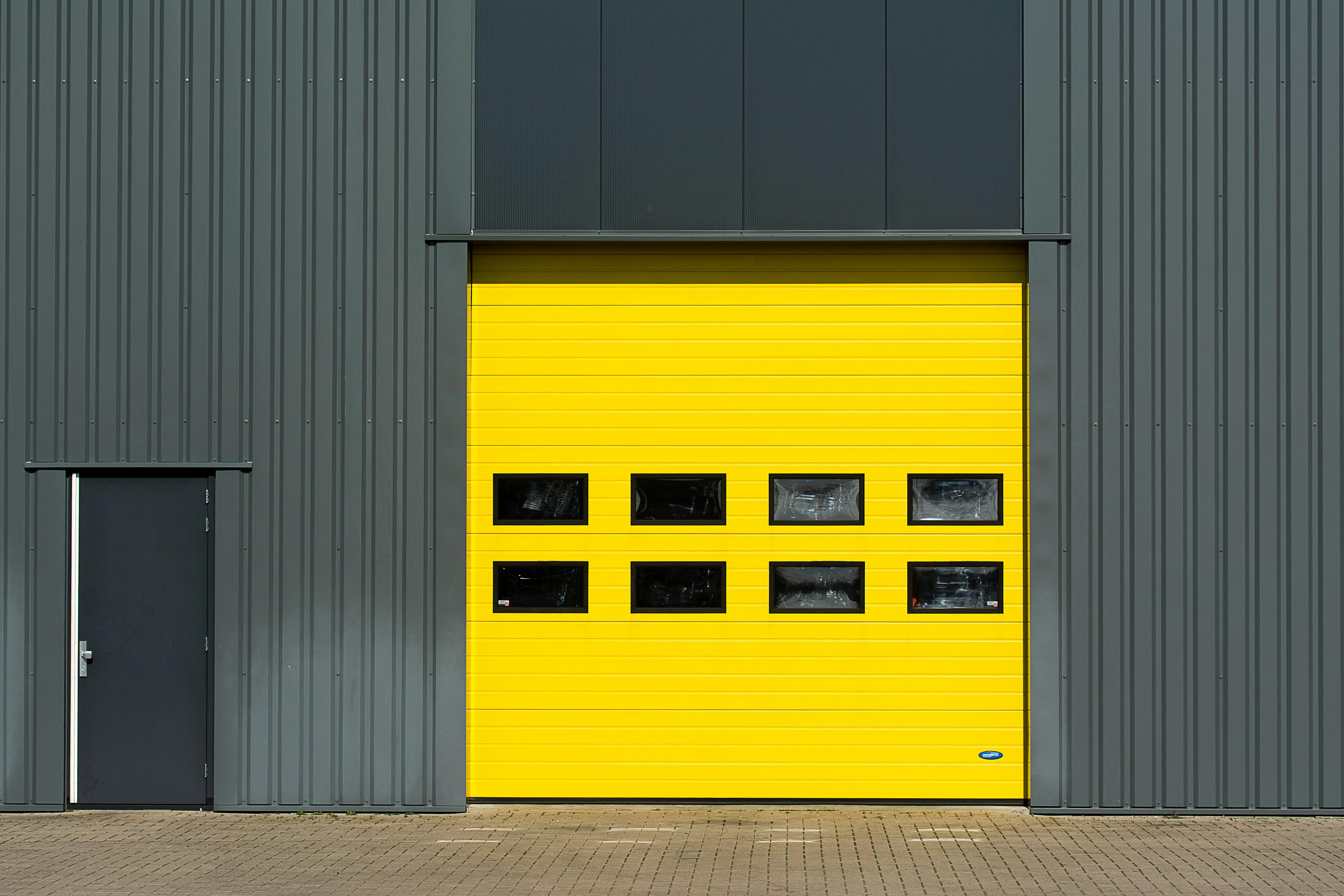 garage doors with windows A sleek industrial structure featuring a vibrant yellow garage door for architectural interest.