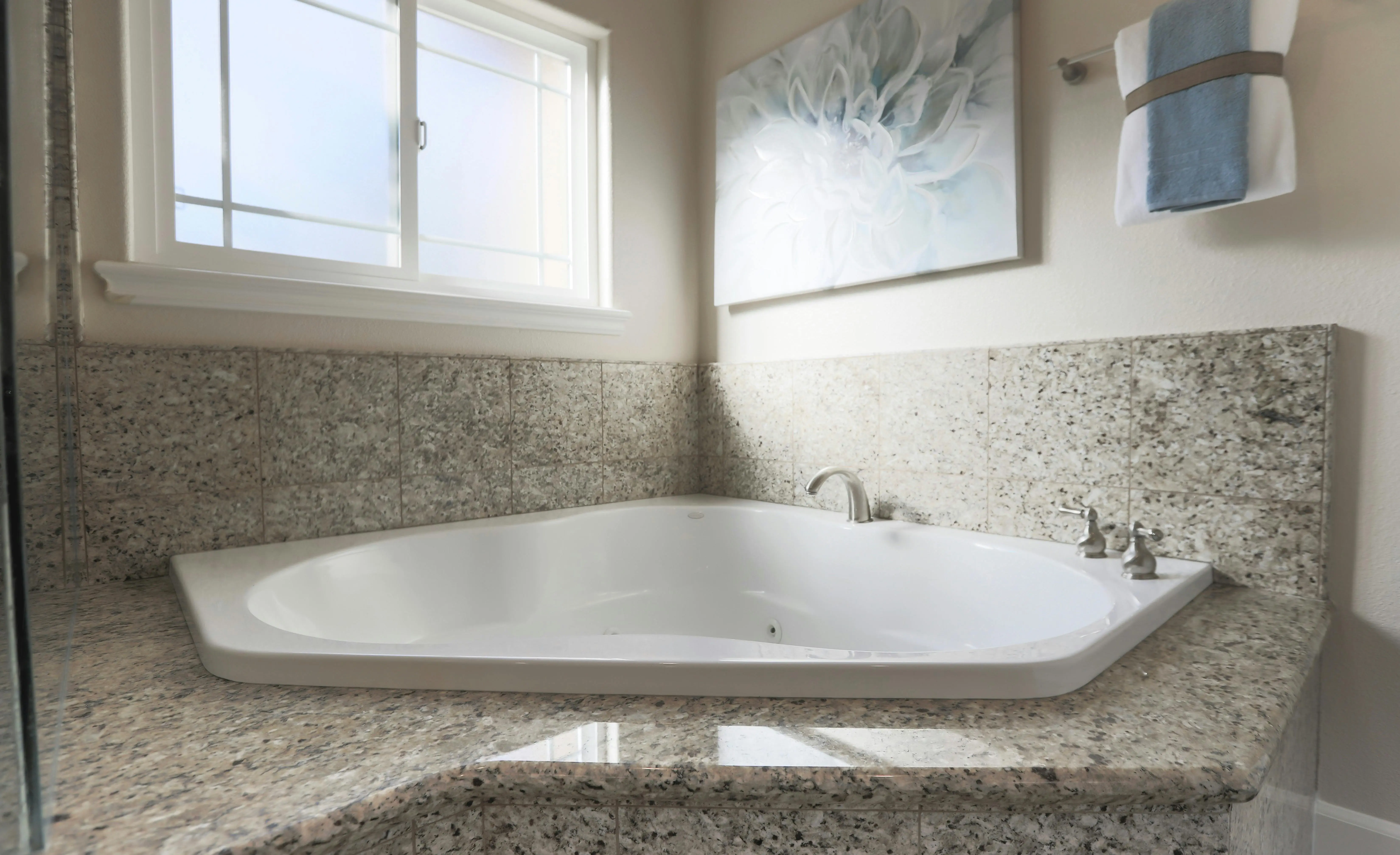 garden tubs Spacious contemporary bathroom featuring a corner bathtub, granite tiles, and elegant decor.