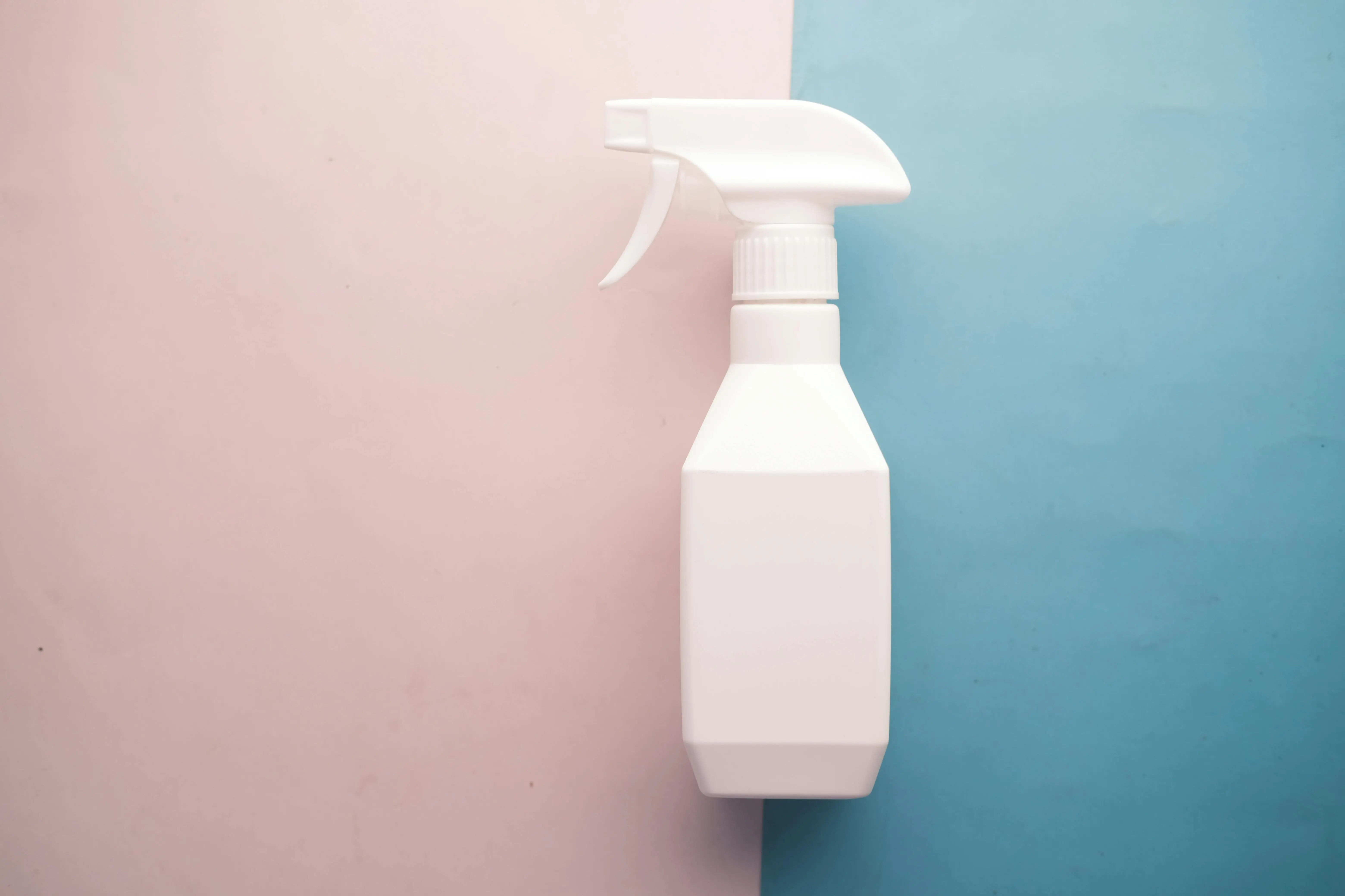 tiny green flying bugs White spray bottle on pink and blue background with copy space, perfect for product mockups.