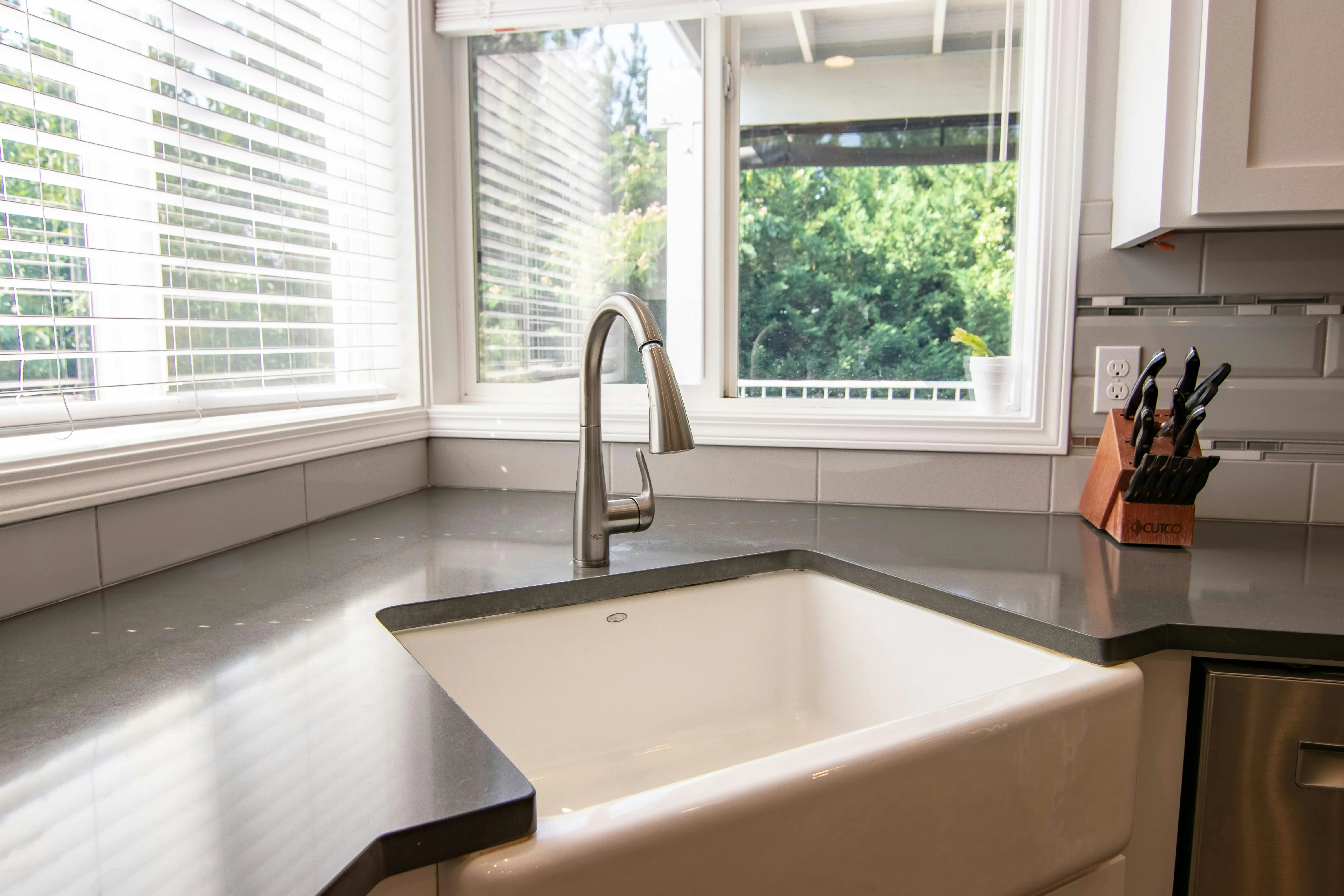 sink parts Stylish kitchen sink with stainless steel faucet and knife block by a bright window.