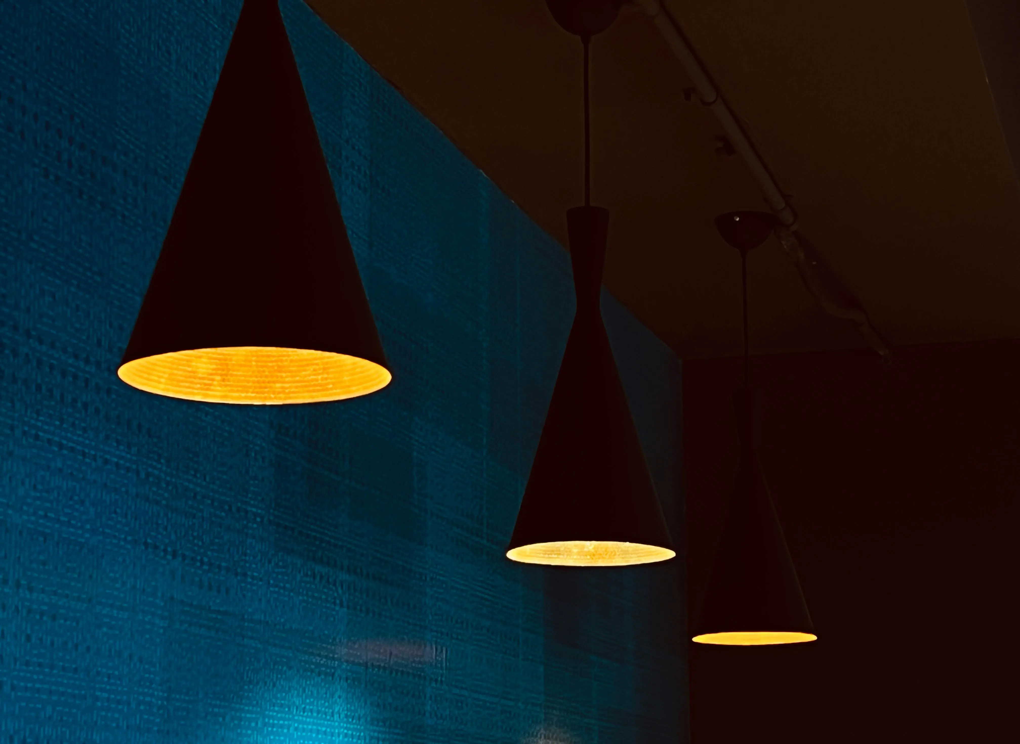 tall table lamps Warm glow from cone pendant lights against a blue textured wall, creating a cozy modern ambiance.