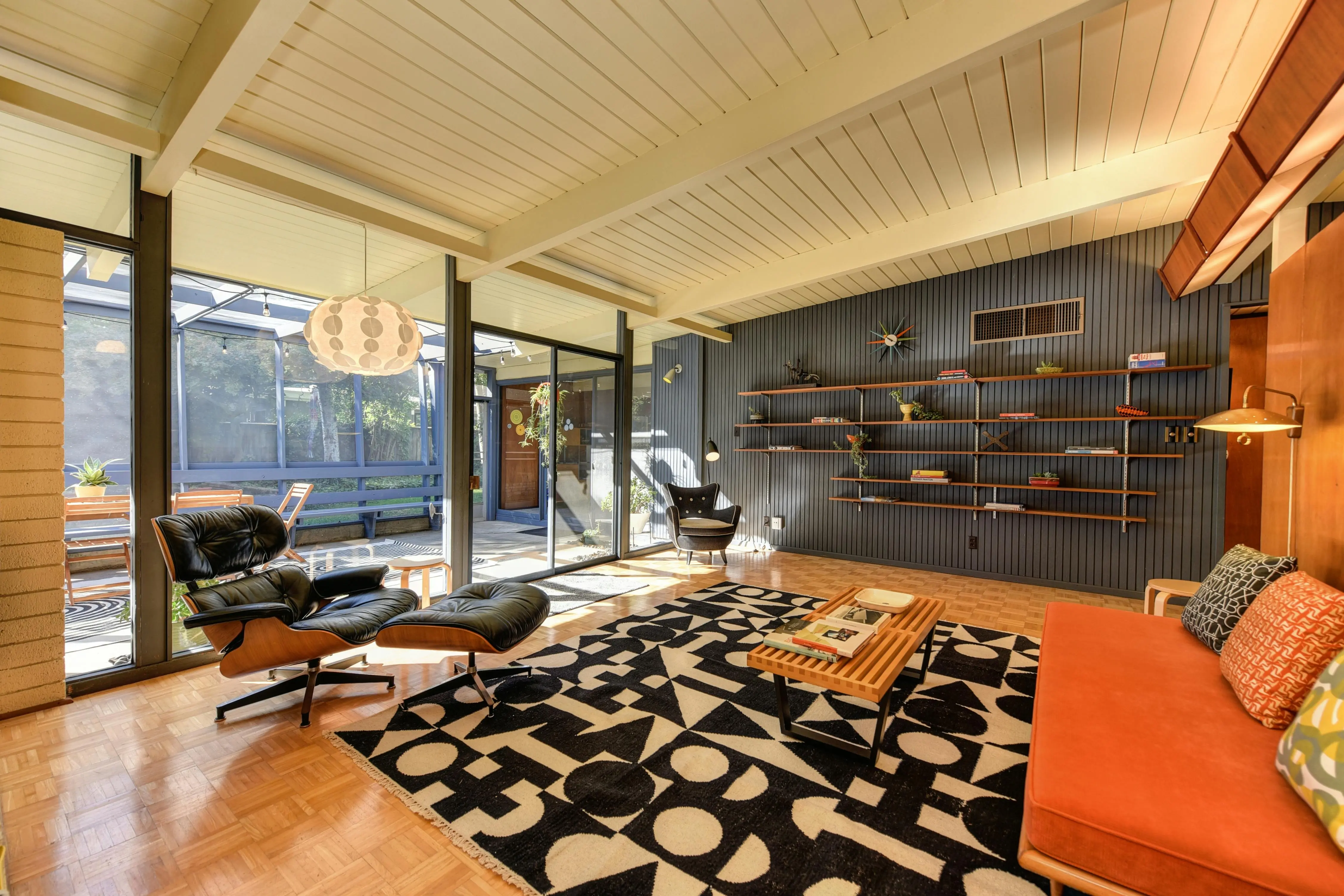 mid century modern art Stylish mid-century modern living room with armchairs, shelves, and natural light.