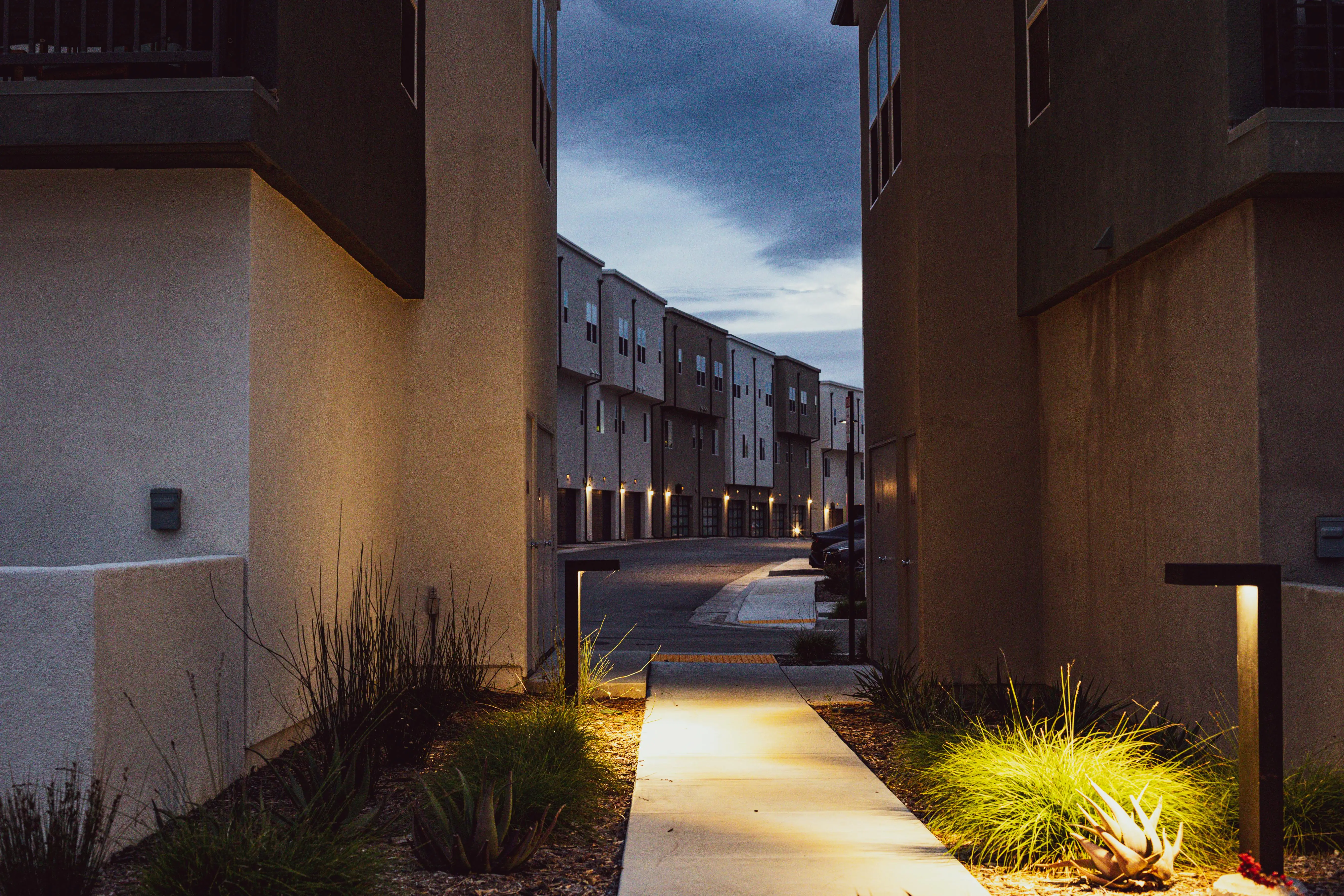 pathway lights A serene view of a modern urban alley at twilight with contemporary architecture and lights.