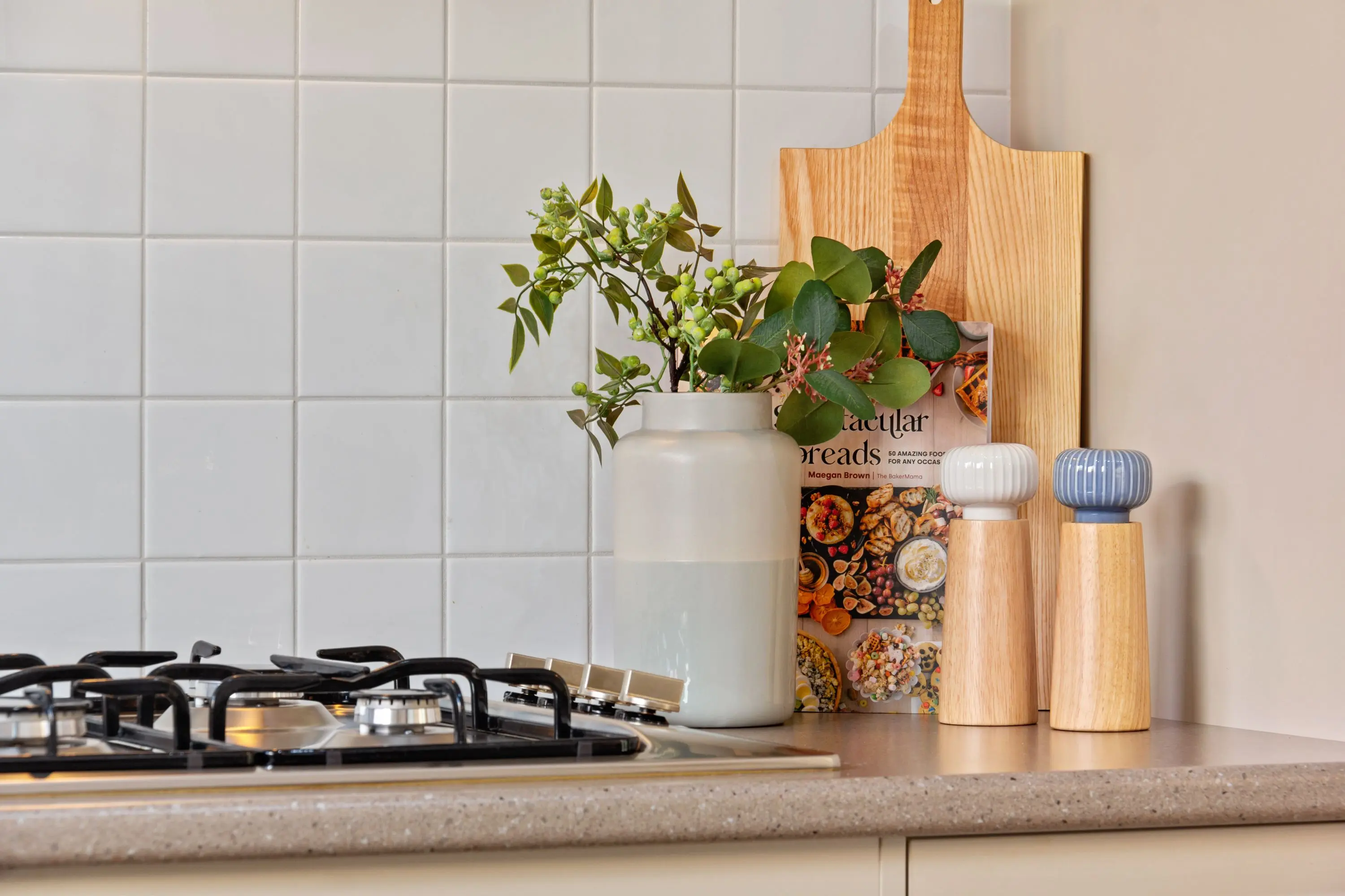 white shaker cabinet Chic kitchen featuring a modern cooktop, decorative vases, and stylish tableware.