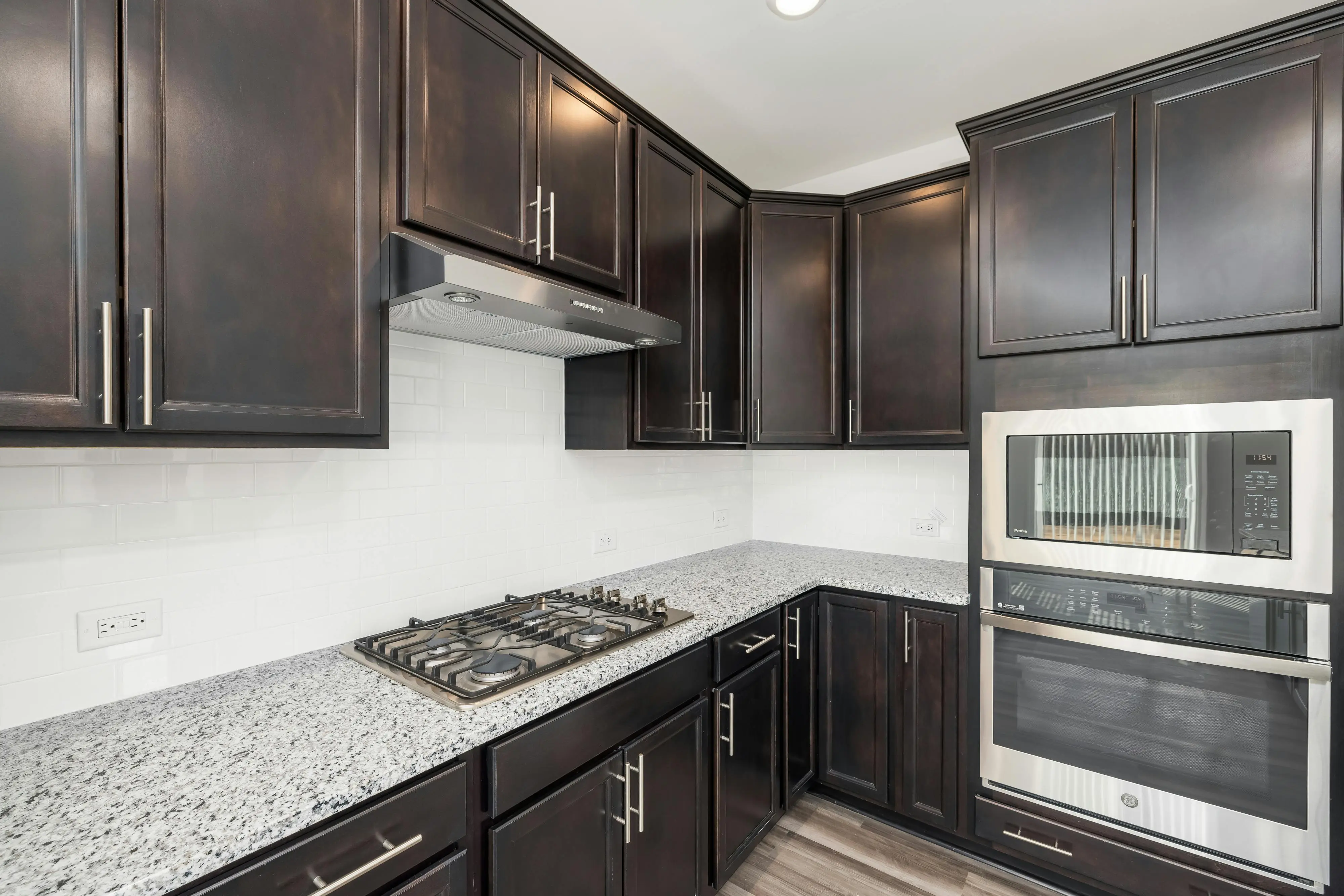 maple cabinets Elegant modern kitchen featuring dark wooden cabinets, sleek granite countertops, and built-in appliances.