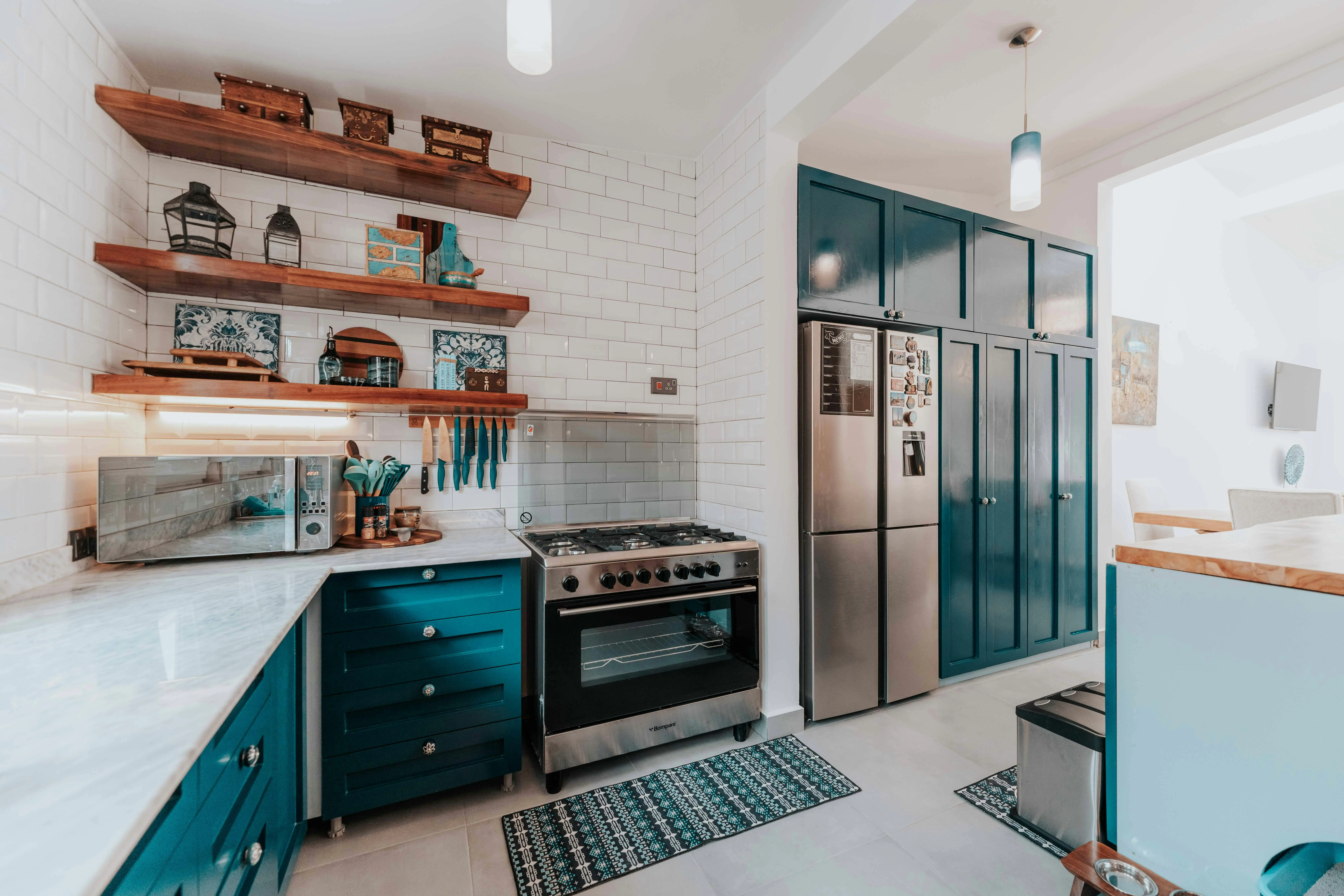 tiny home kitchen Stylish kitchen featuring sleek blue cabinets, stainless steel appliances, and wooden shelves.