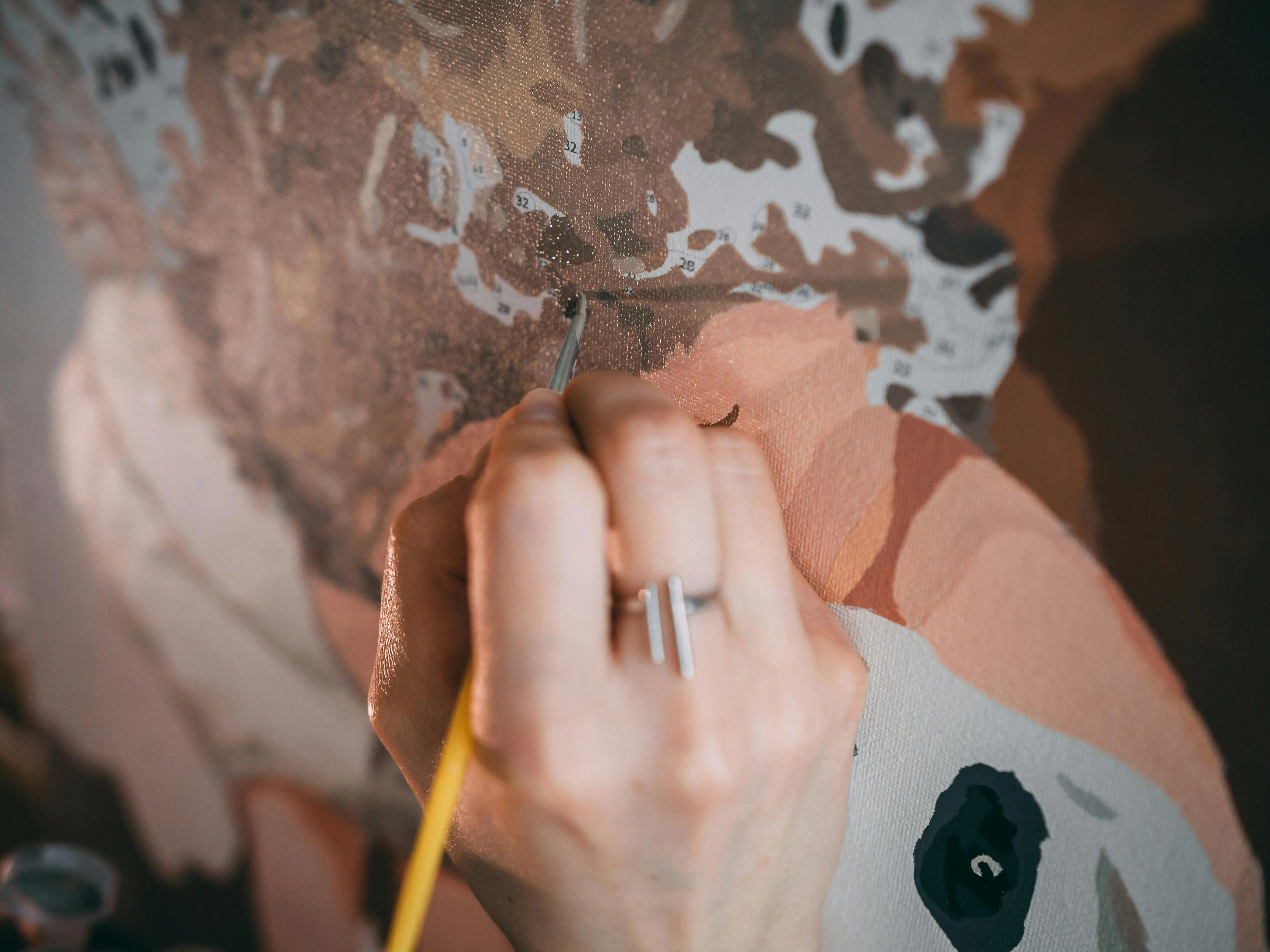 famous and easy paintings Hand meticulously painting a detailed canvas, showcasing artistic skill and precision indoors.