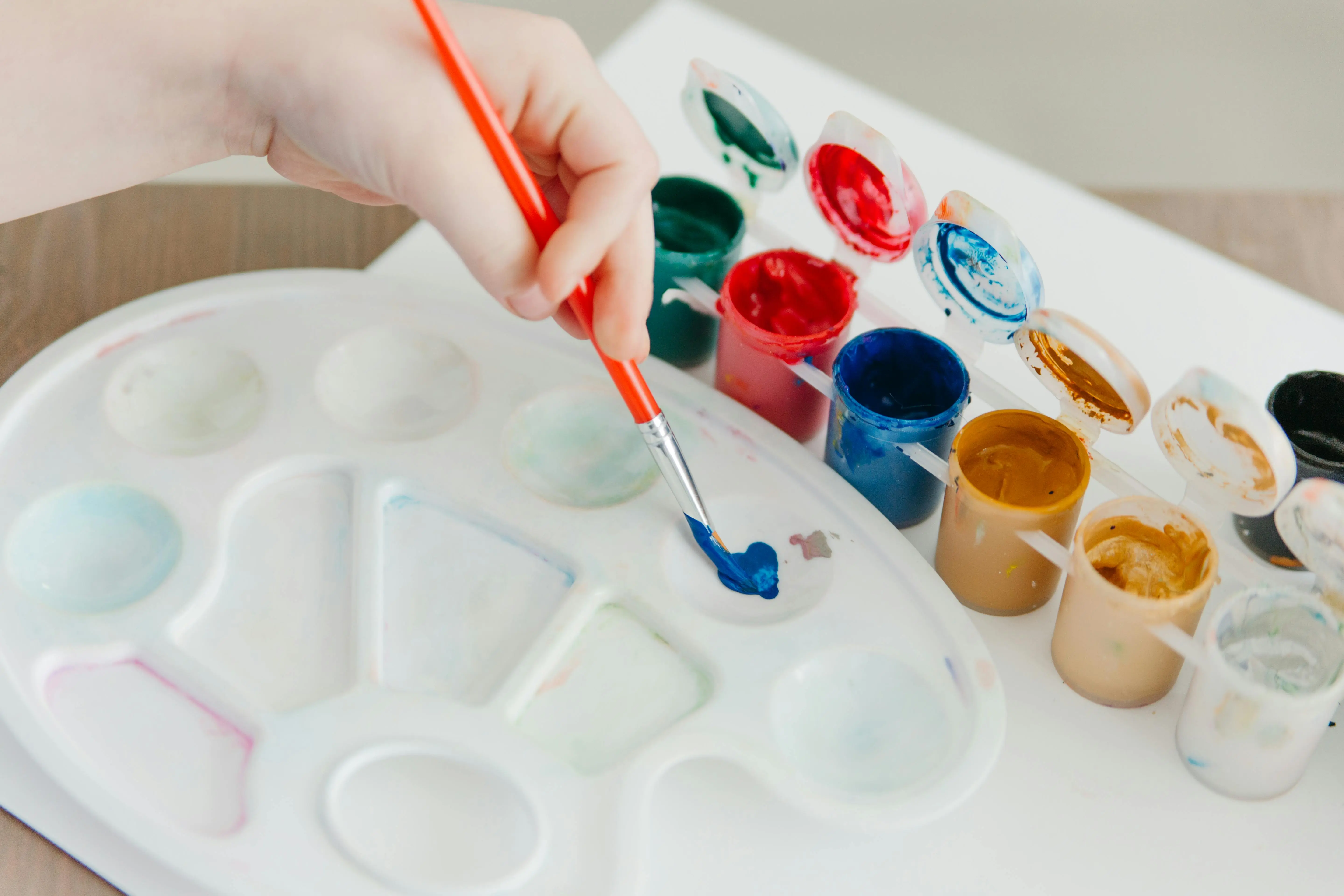 famous and easy paintings Close-up of a hand painting with vibrant acrylic colors on a palette, showcasing artistic creativity.