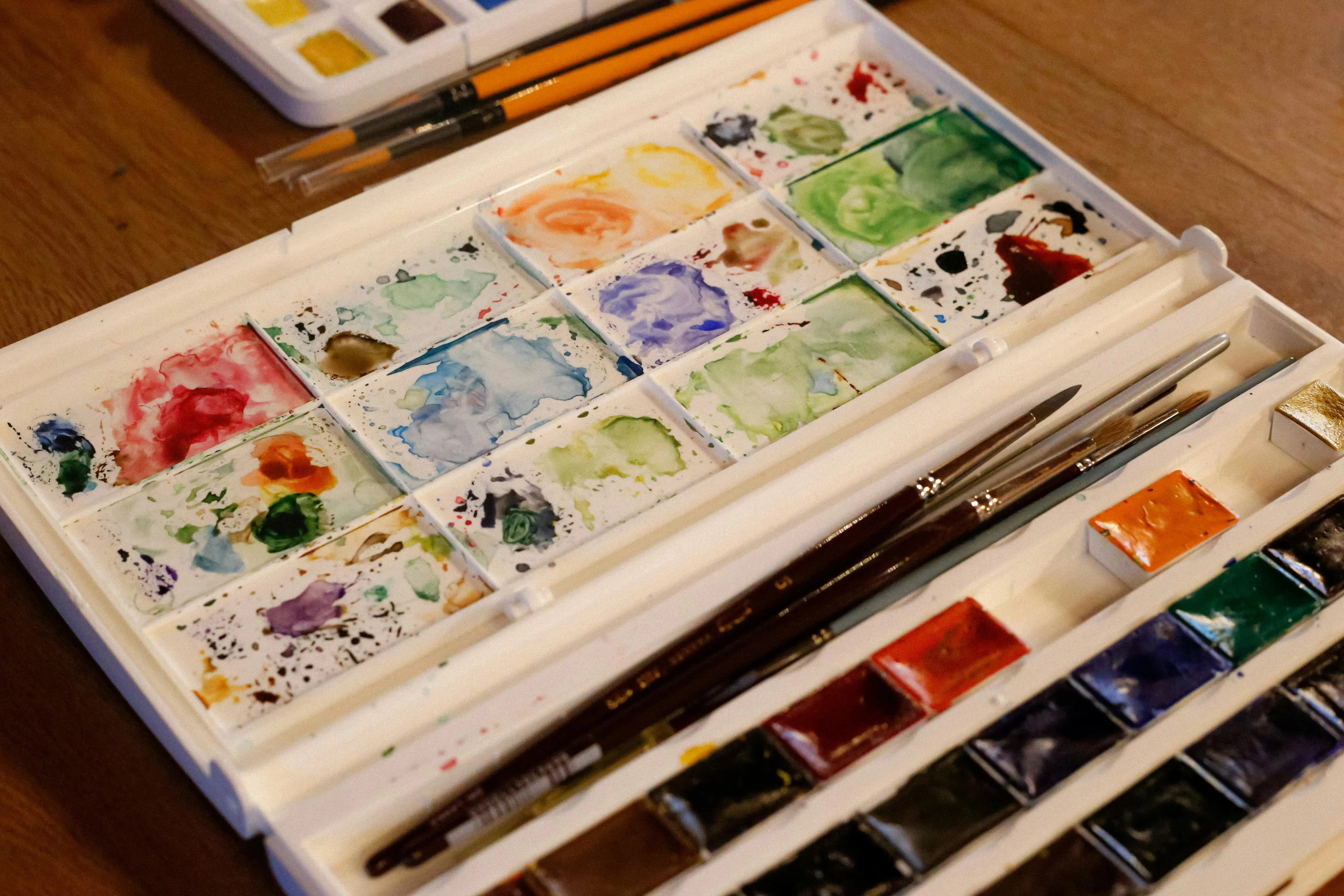 watercolor paint set A vibrant watercolor paint set and brushes on a wooden table, perfect for artists.