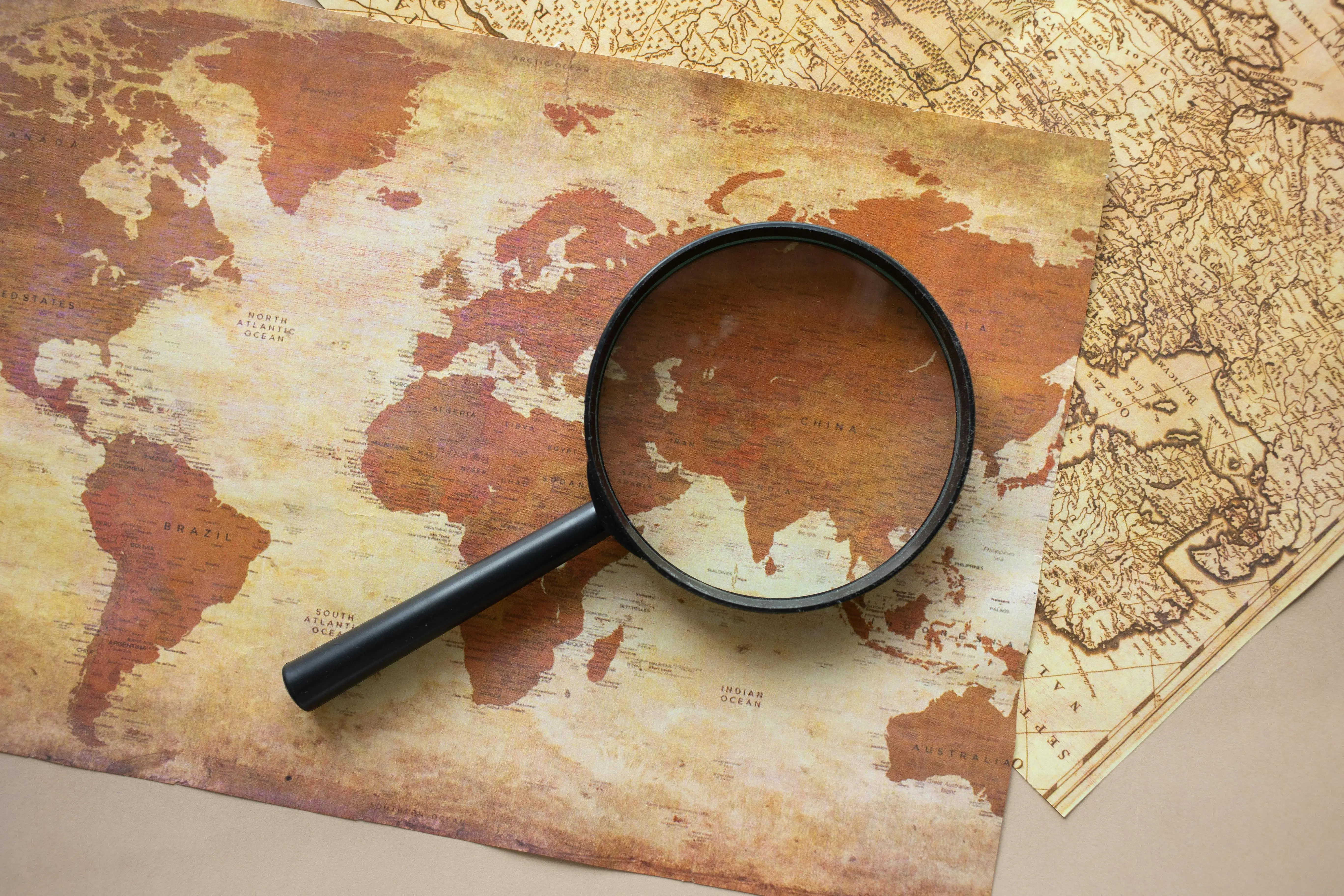 spiders that look like brown recluse A top view of a vintage world map with a magnifying glass highlighting regions for exploration.