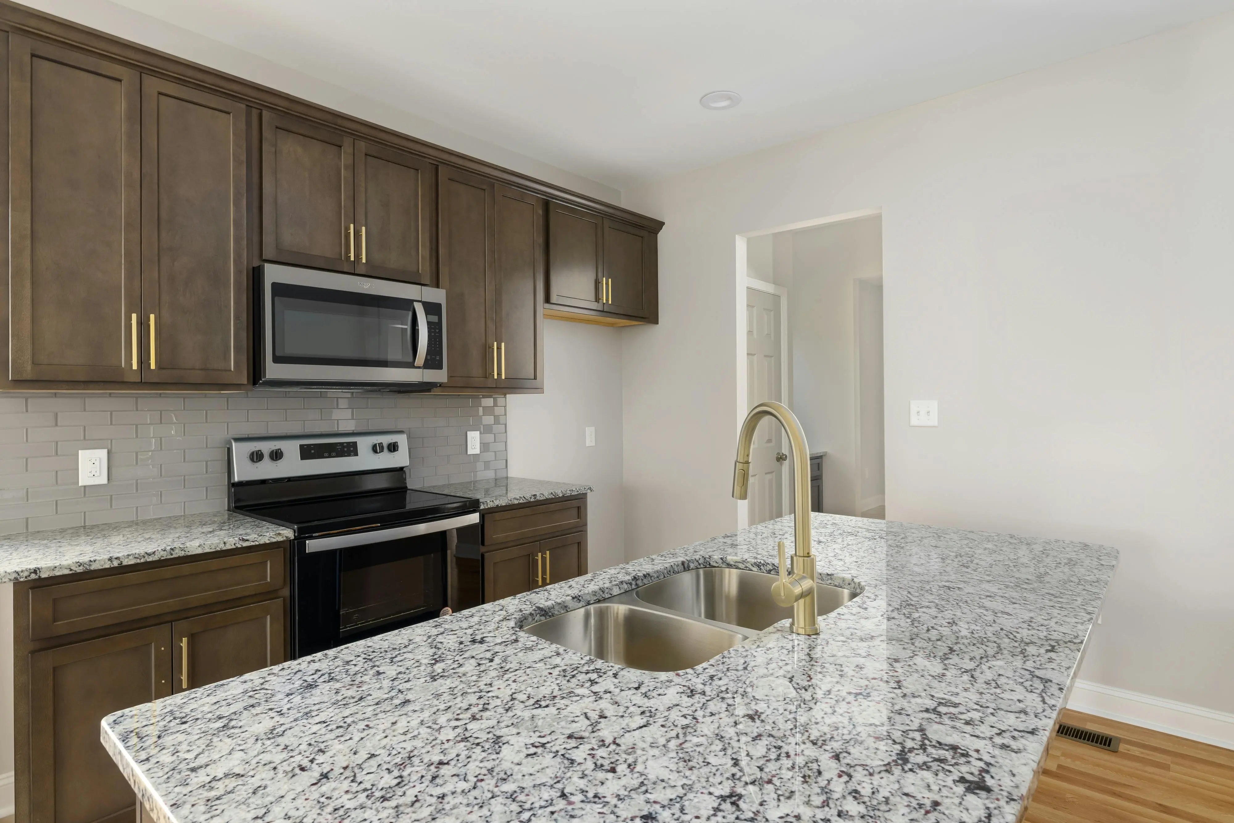 white shaker cabinet Elegant modern kitchen featuring a marble countertop, stainless steel appliances, and wooden cabinets.