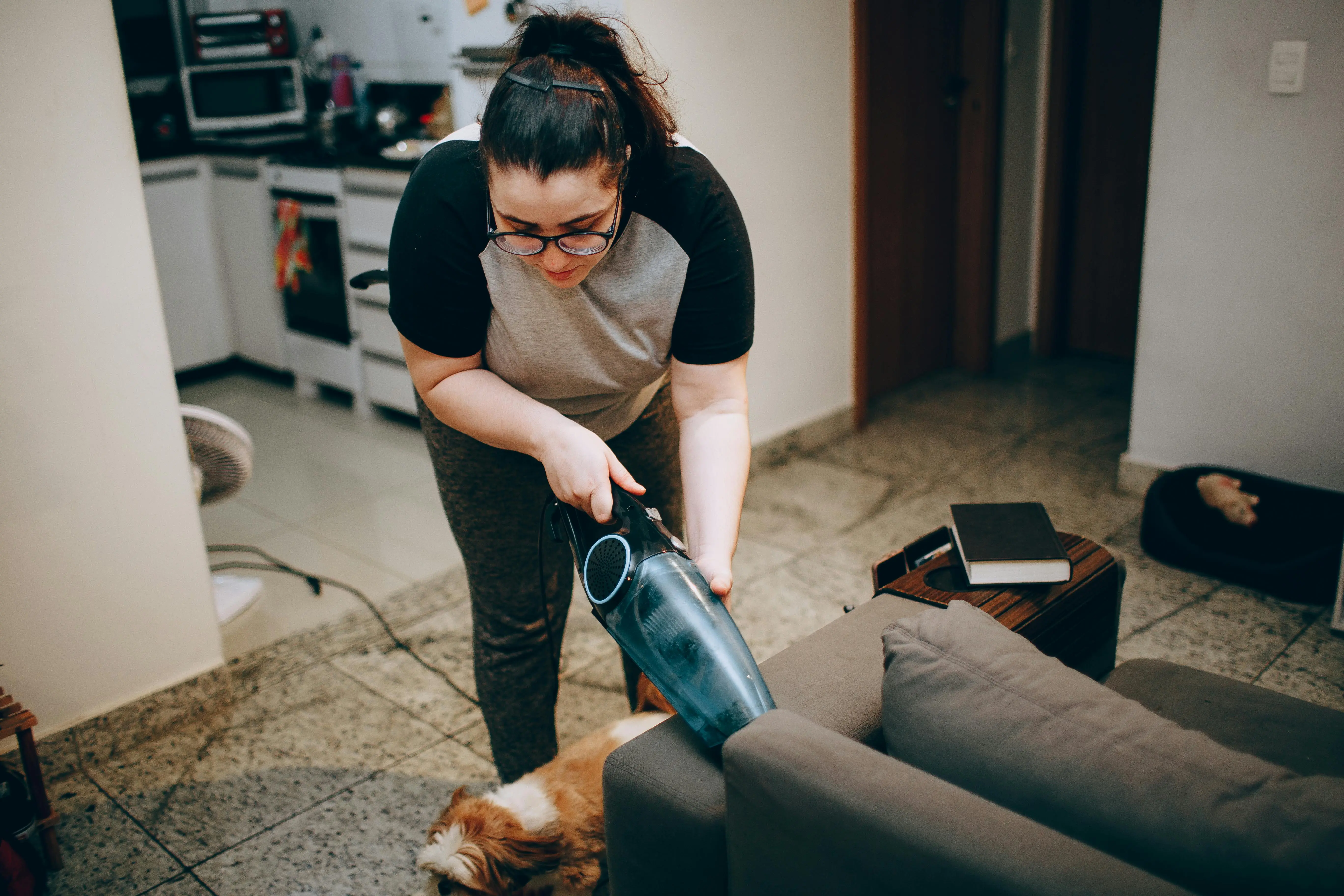 small sofa bed with storage Woman cleaning a living room with a vacuum, showing a cozy and tidy home environment.