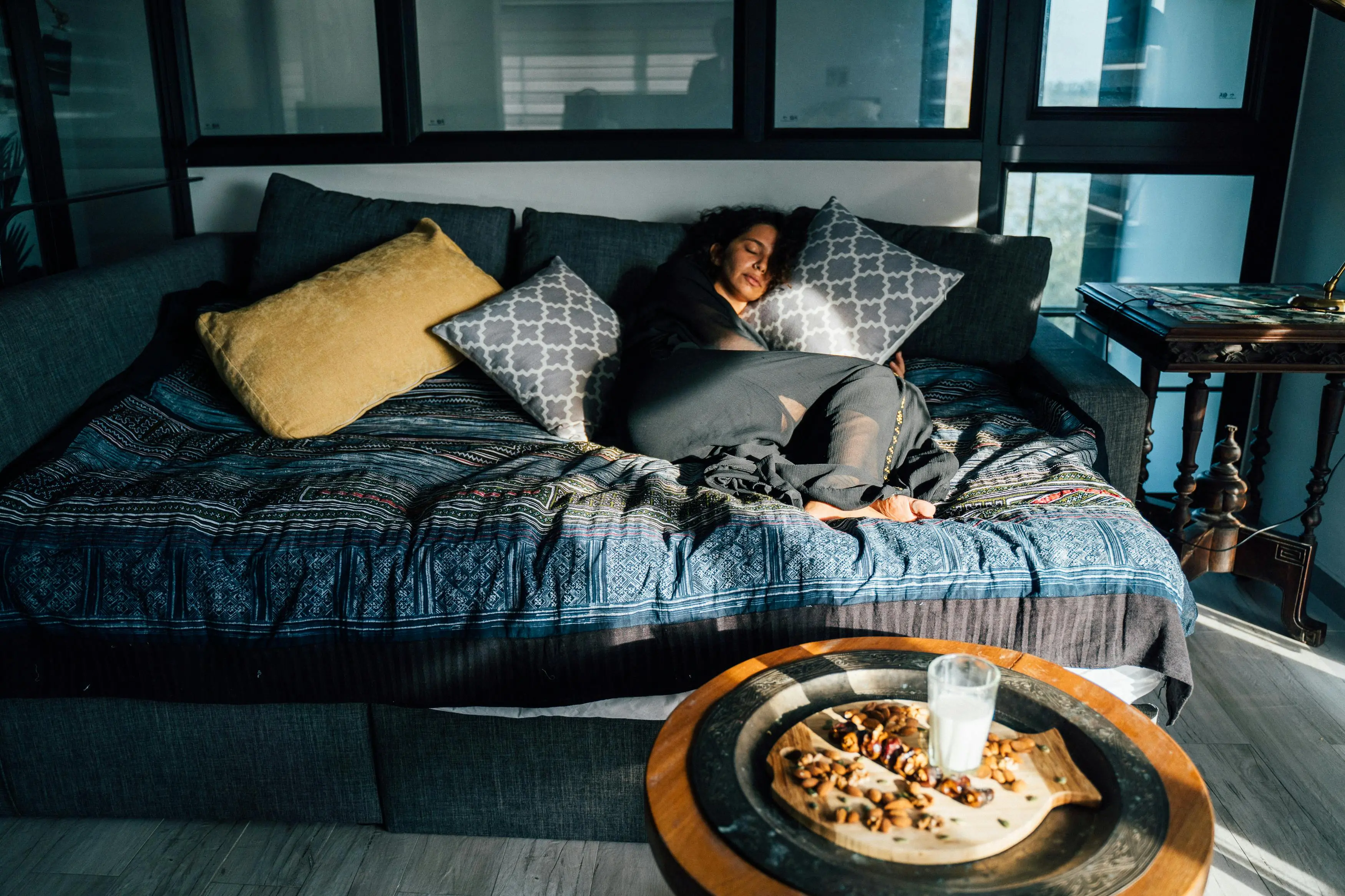 small sofa bed with storage A woman peacefully napping on a comfortable bed with sunlight streaming in.