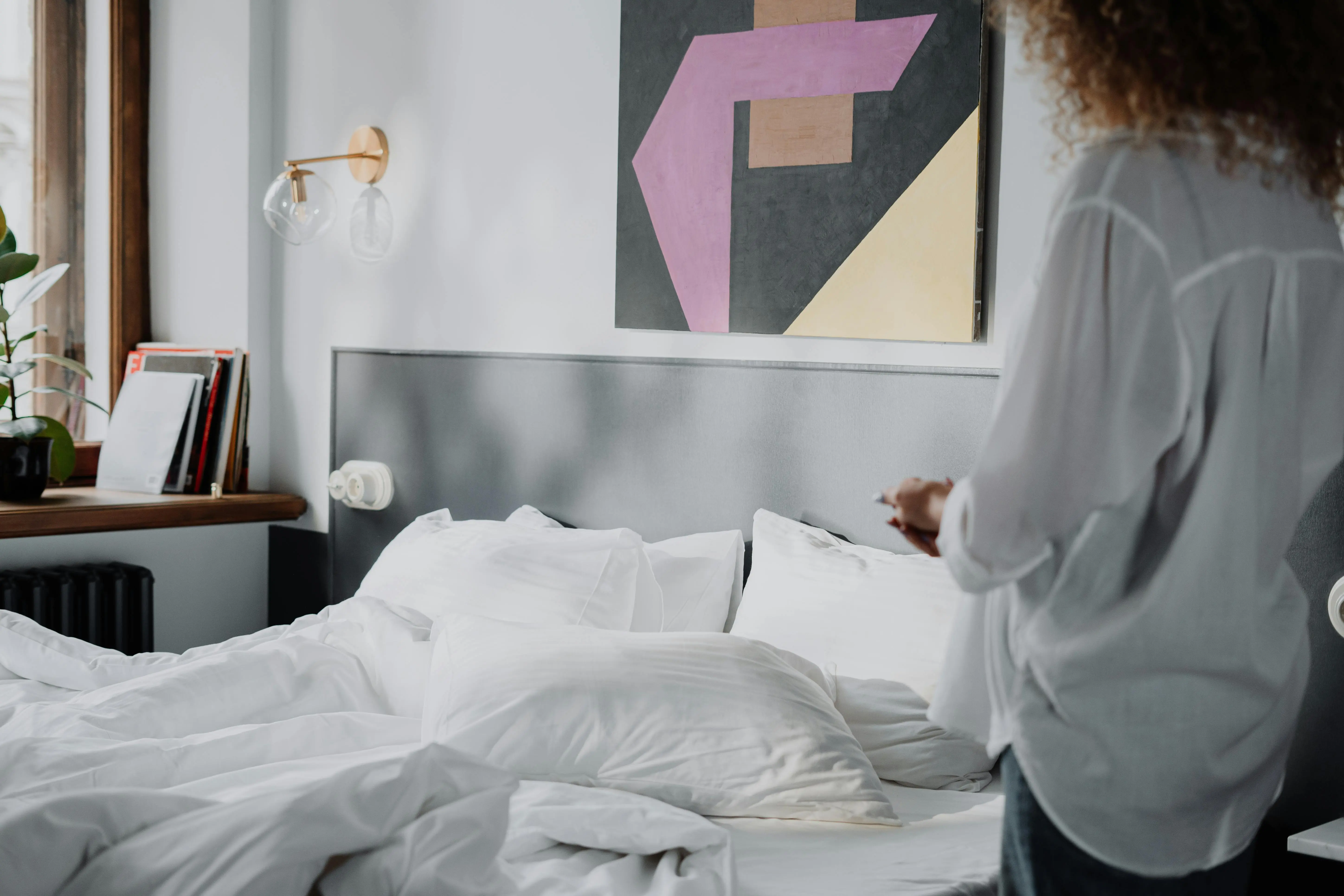 get blood out of clothes A serene bedroom interior with bright white linens, wall art, and natural light.