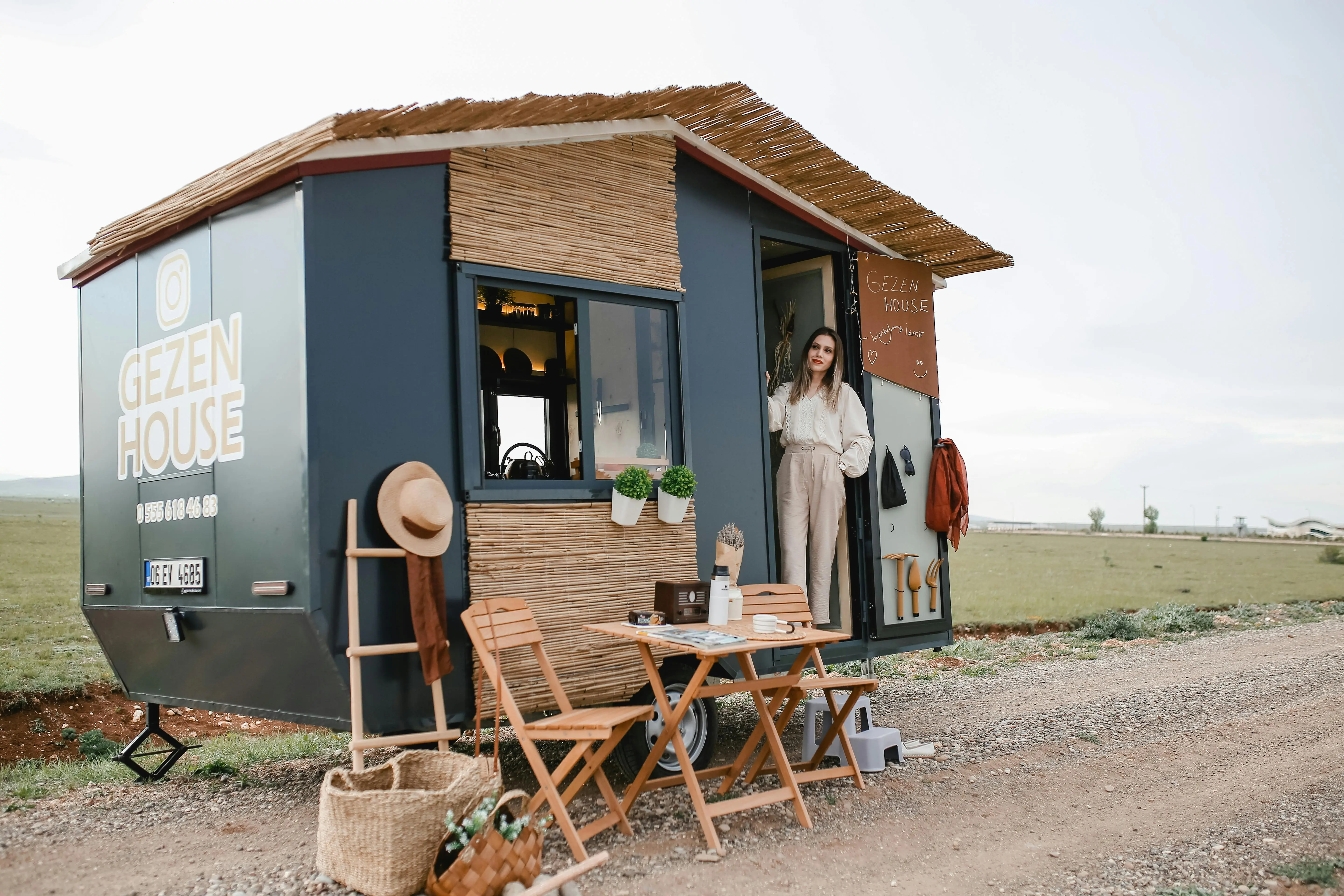 tiny home with 2 bedrooms Woman standing by a stylish mobile home in an open field, ideal for travel enthusiasts.