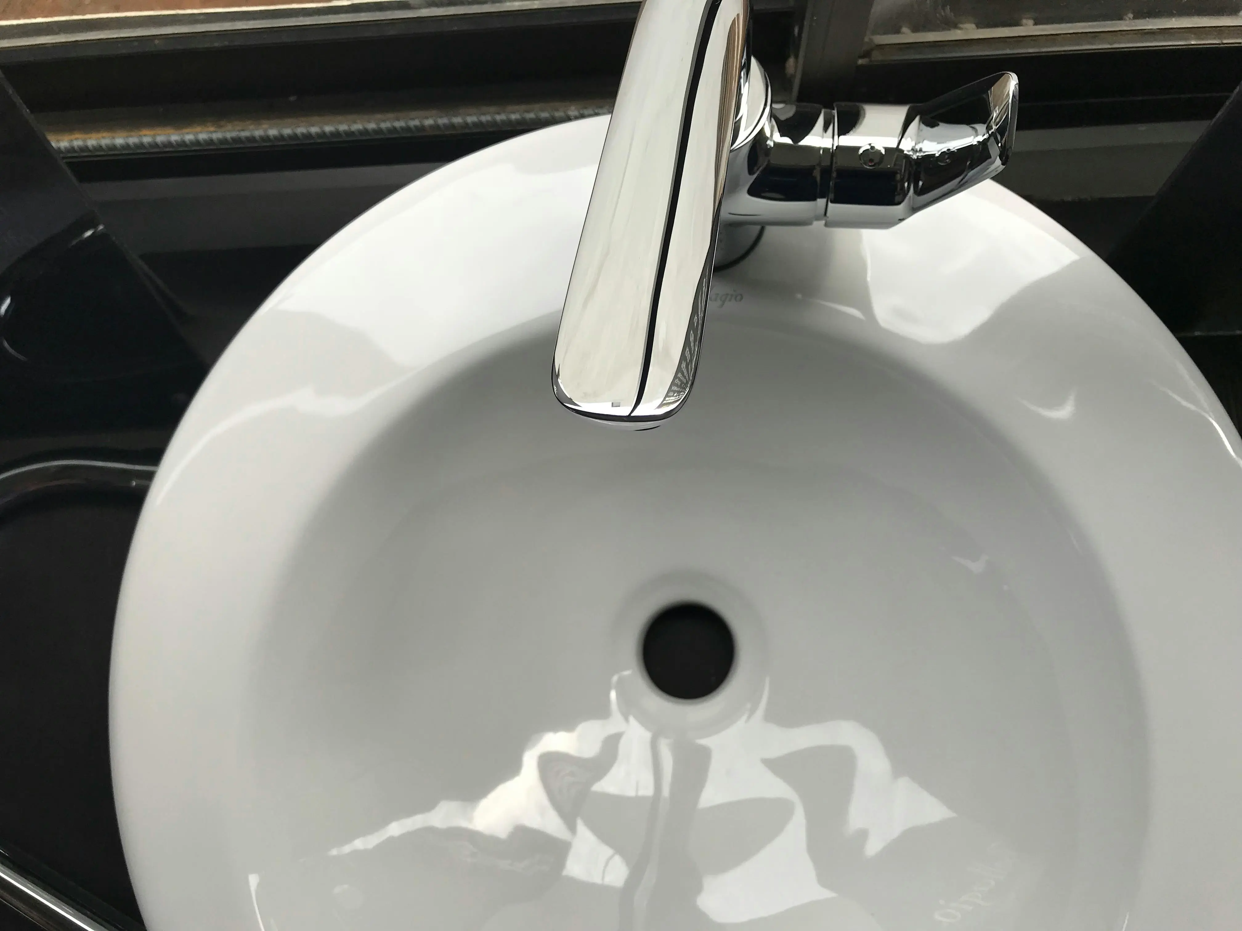 tiny home tips and tricks Close-up image of a modern stainless steel faucet and ceramic sink, highlighting cleanliness and hygiene.