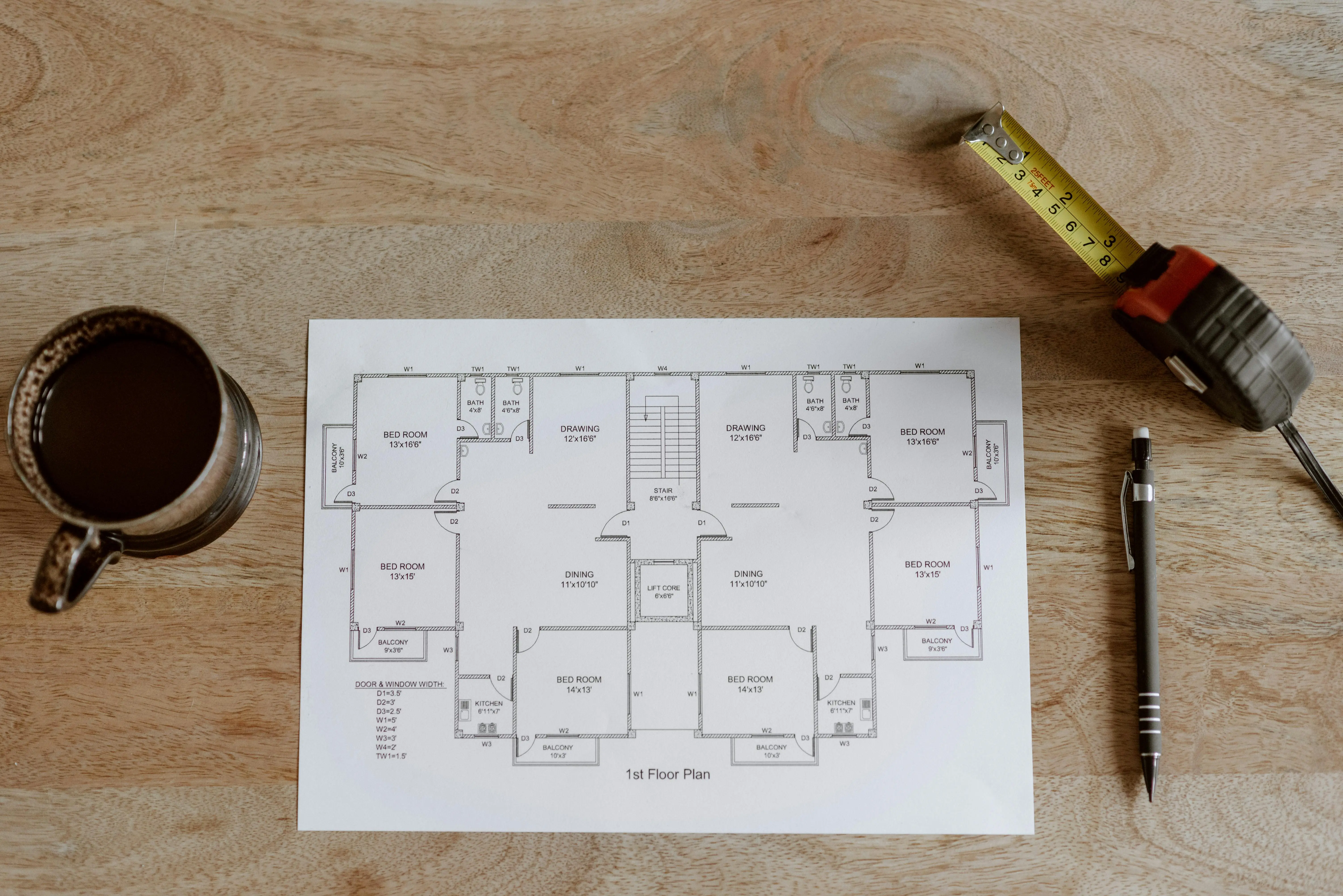 tiny house living tips Top view of set of plan of room with tape measure and pen for work for architect with cup with coffee on wooden table in soft daylight