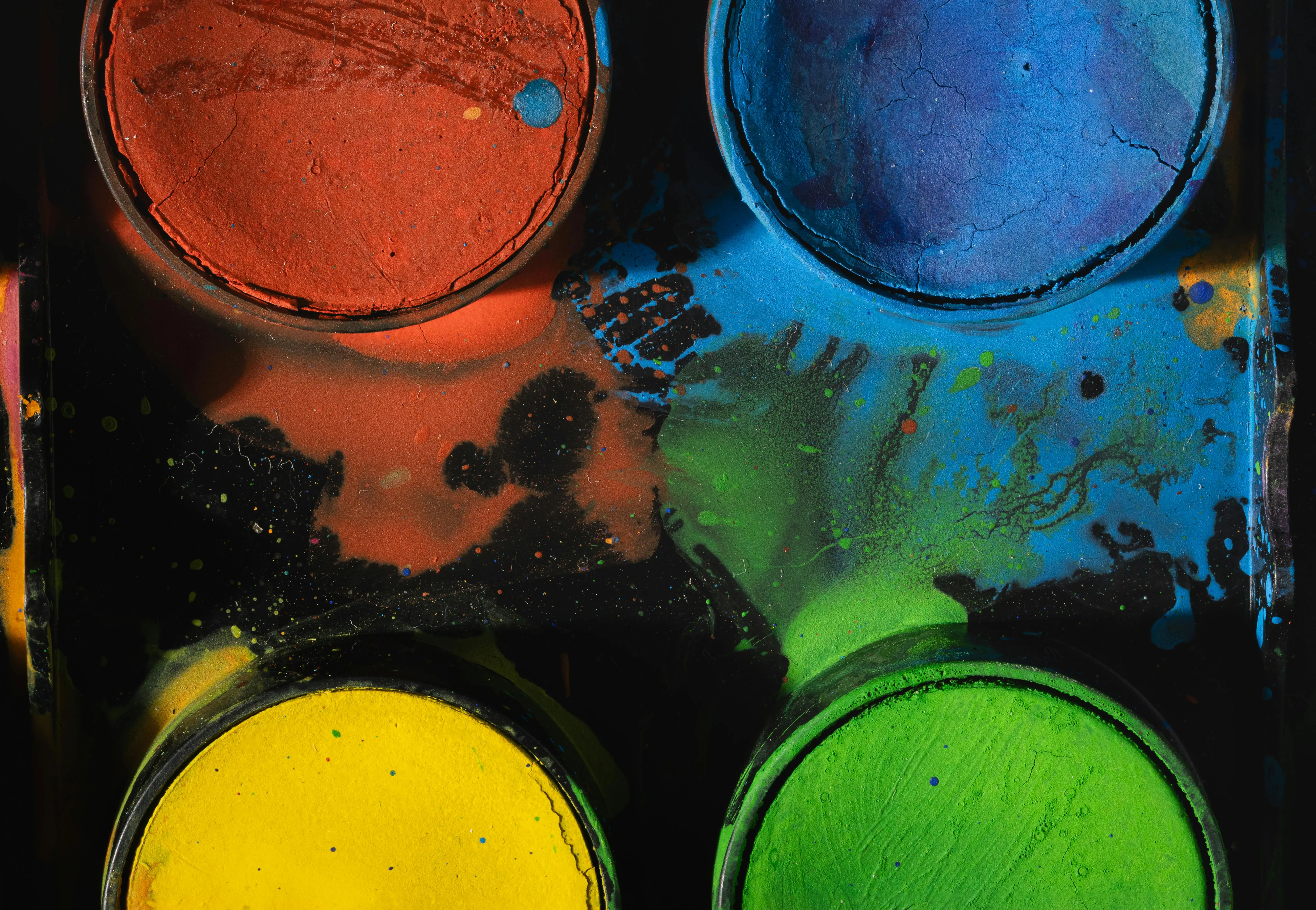 watercolor paint set A close-up of a colorful paint palette showing vibrant pigments in red, blue, yellow, and green.