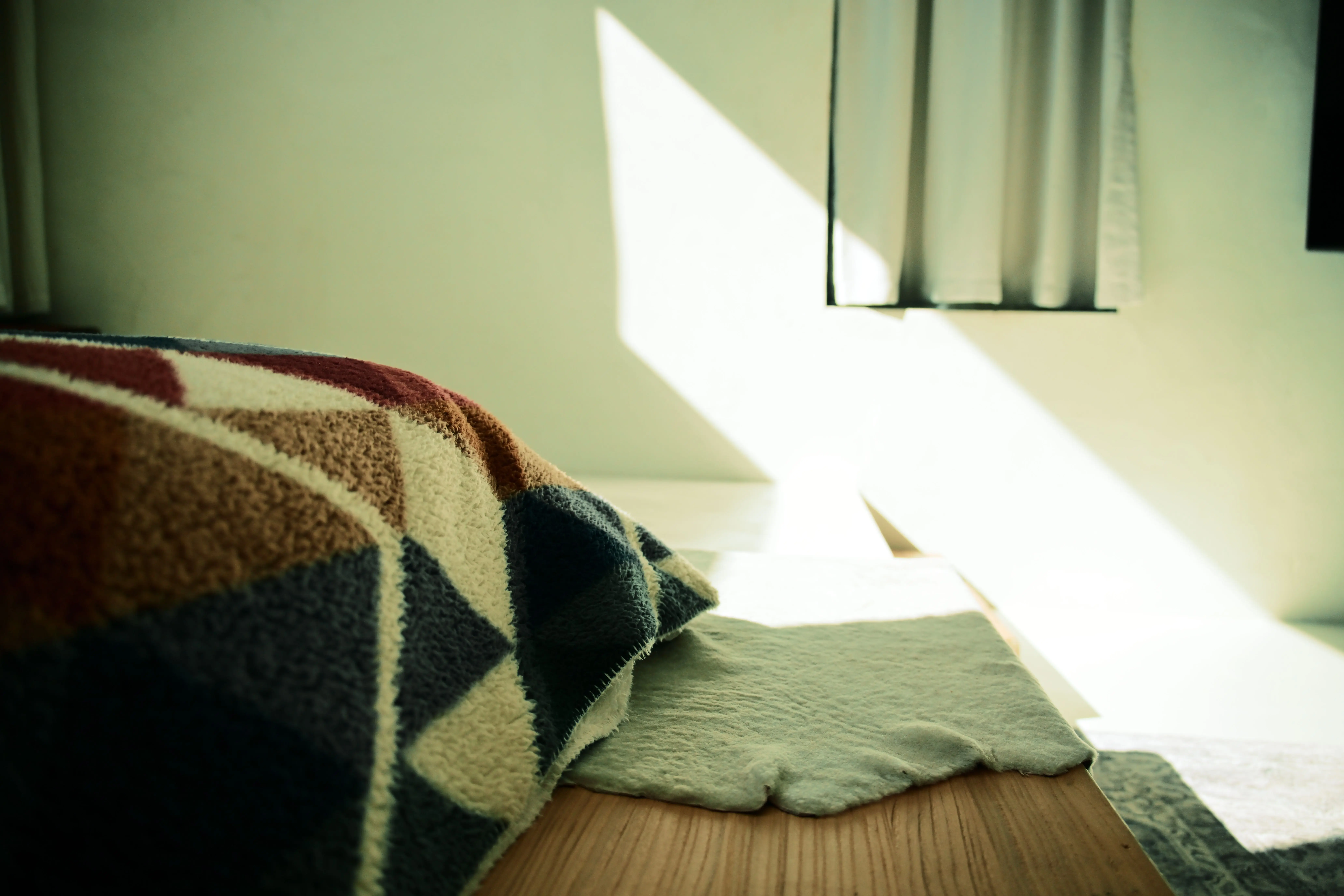 why make trims and doors satin paint Sunlight streaming through curtains onto a colorful patterned blanket in a cozy bedroom setting.