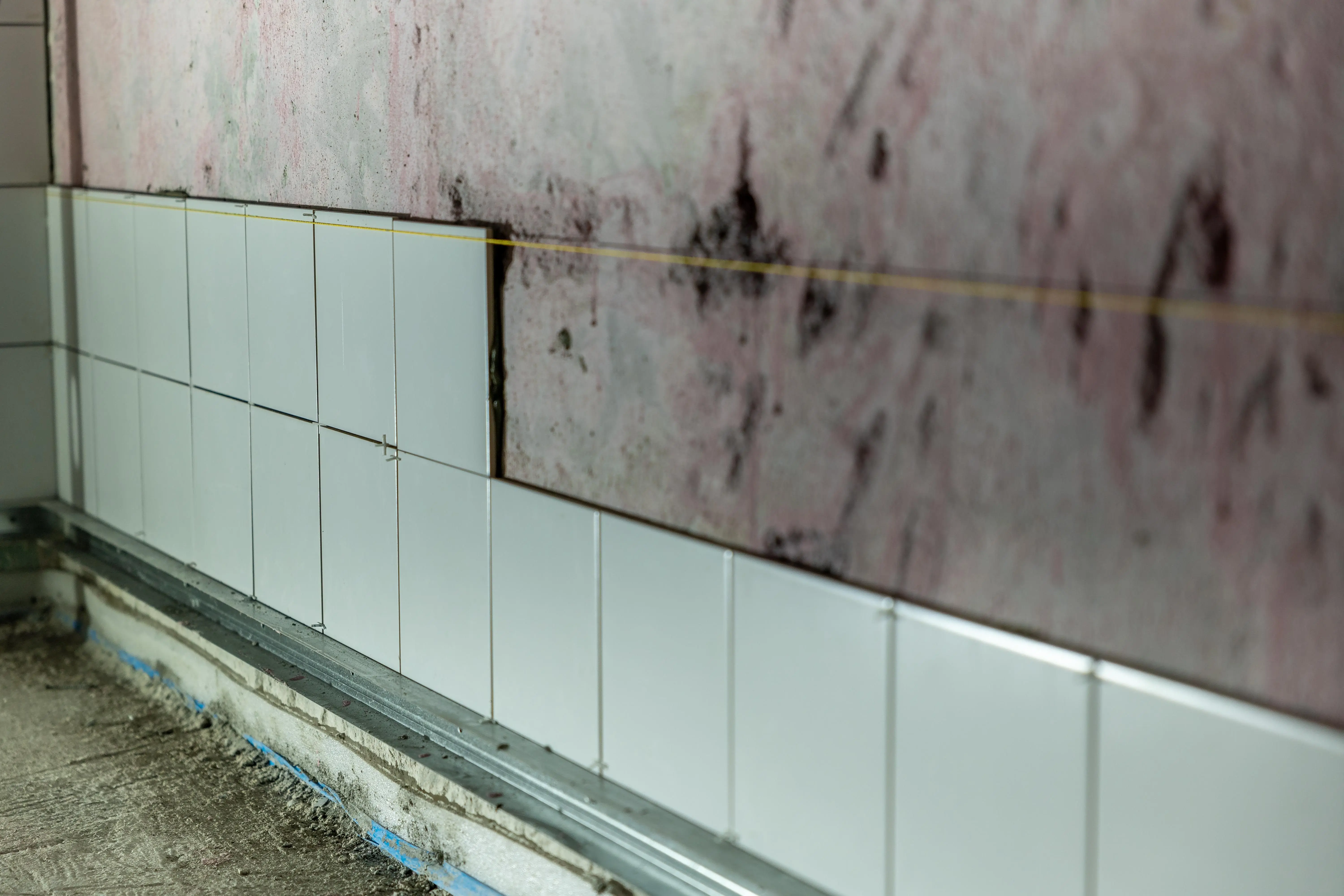gray tile Close-up of partially tiled wall in a construction area, showcasing incomplete renovation work.