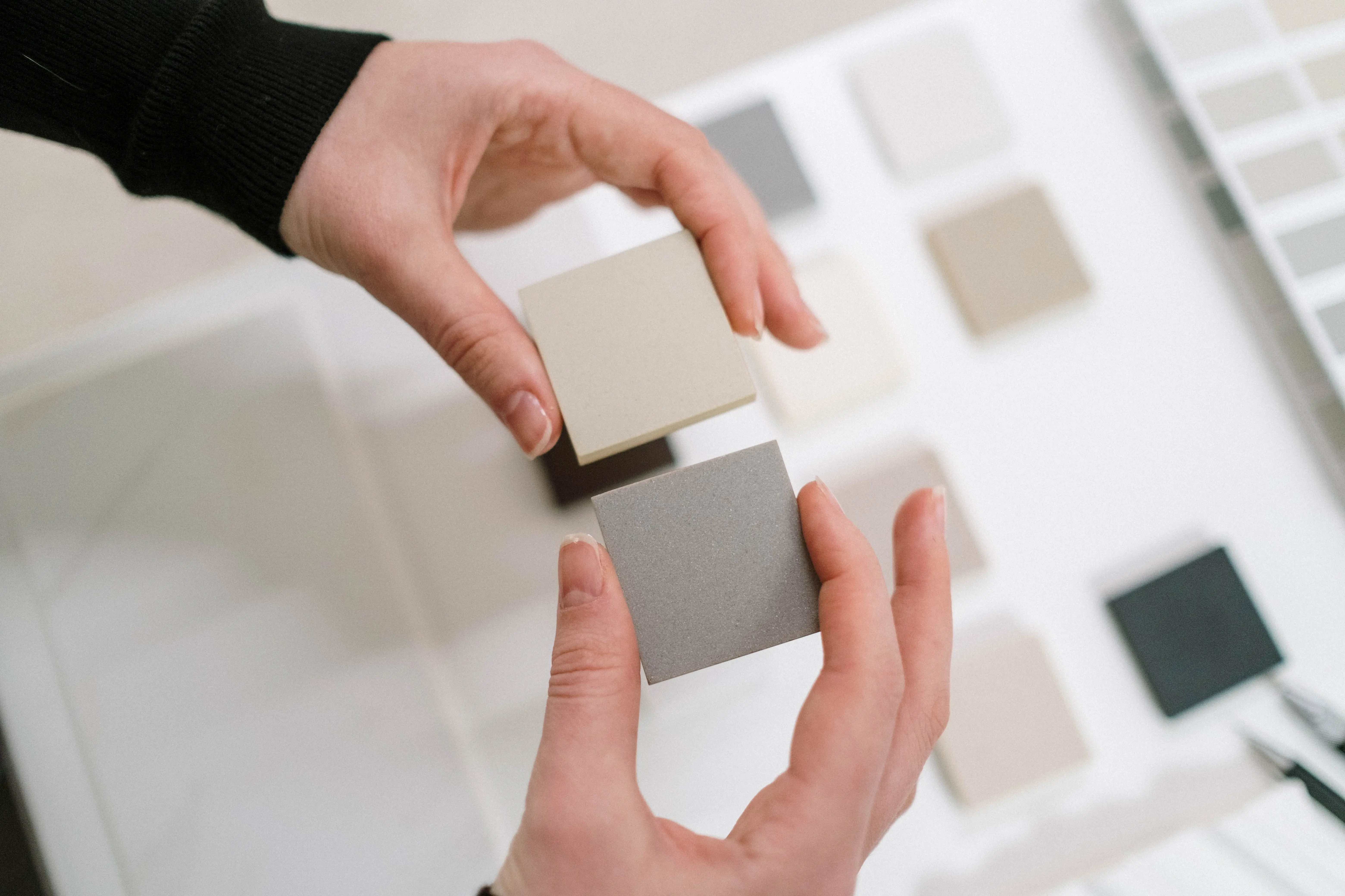 gray tile Hands holding neutral color swatches for interior design selection.