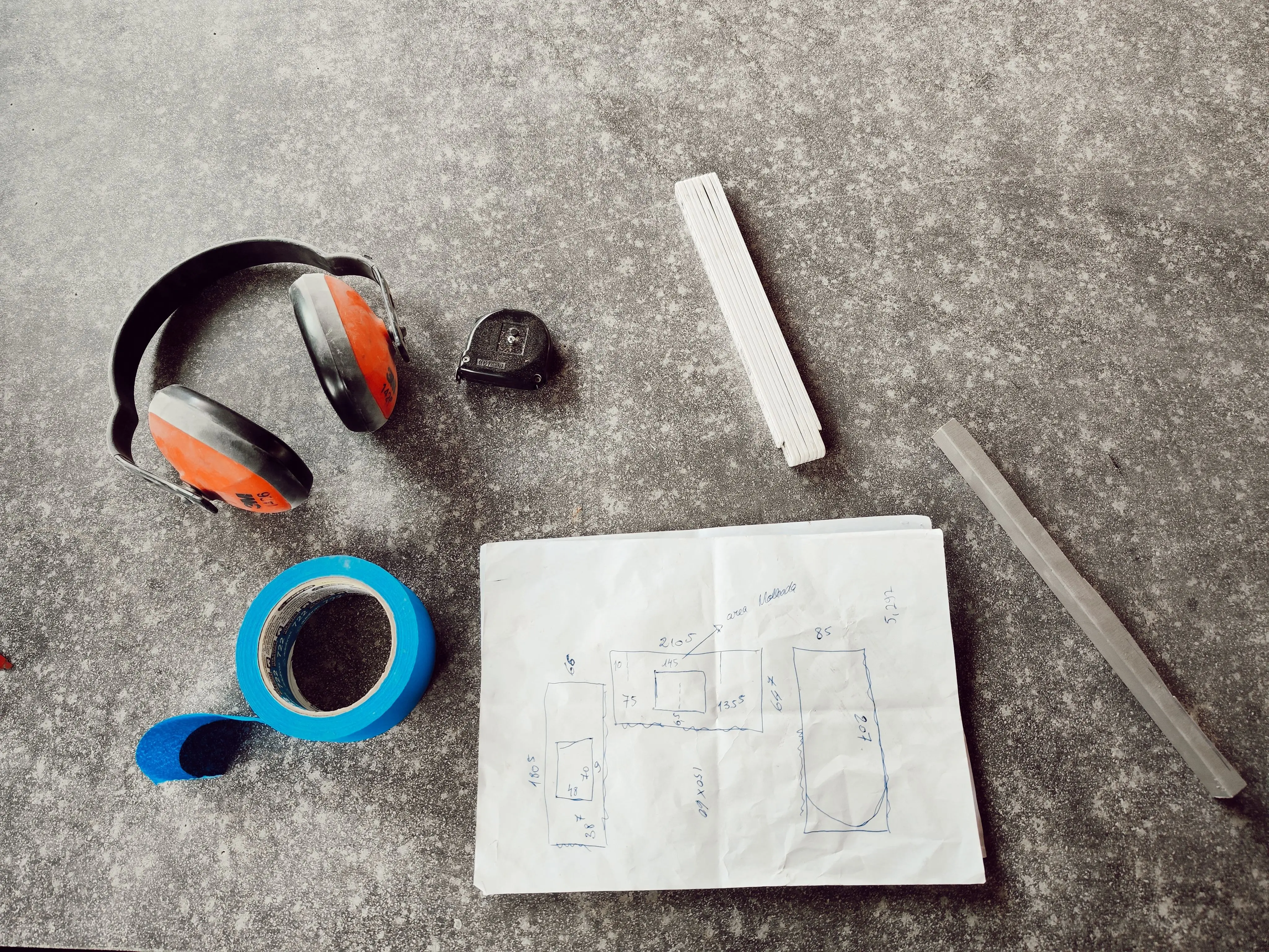 mid century modern kitchen island Overhead view of engineering tools including headphones, tape, and a sketch on a workbench.